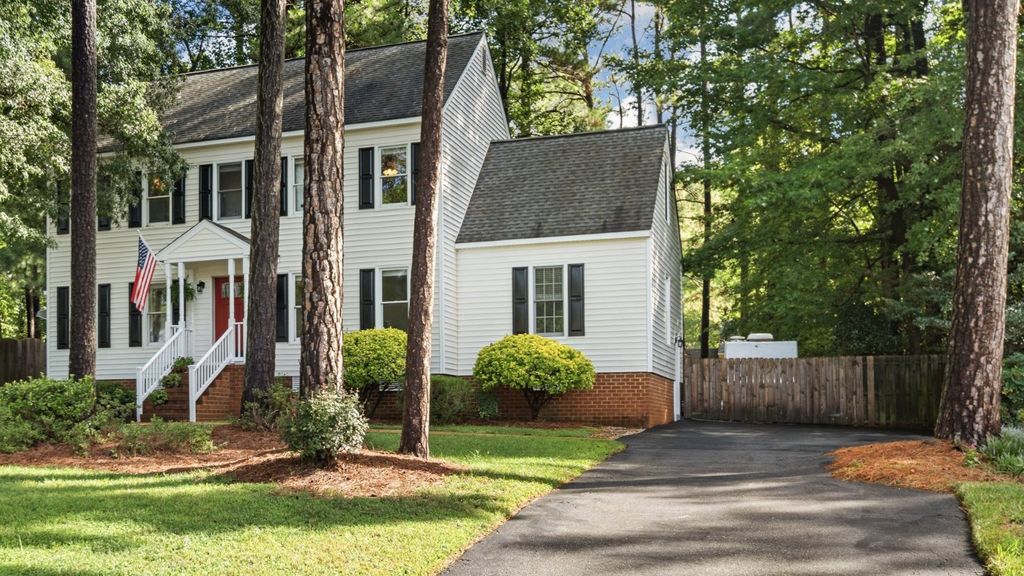 A white colonial with a red door and tall pines in Foxcroft, Midlothian, Virginia