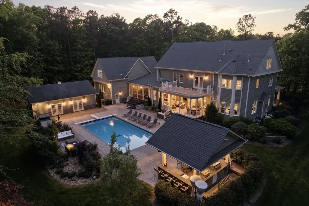 Twilight aerial of the back of a Mountain Run home with a pool, pool house, and detached garage