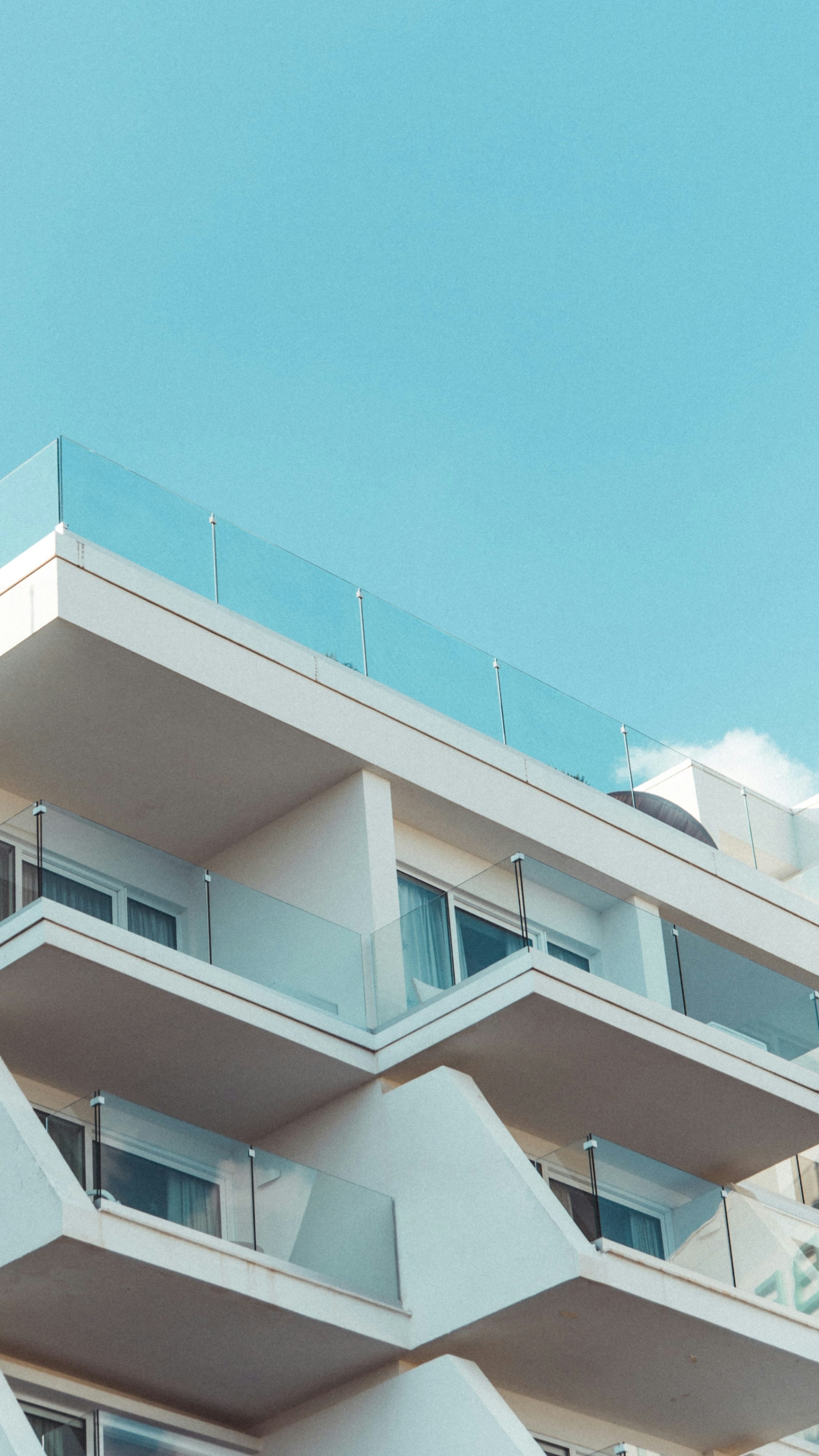 A multi-storey apartment building with stacked balconies under a blue sky