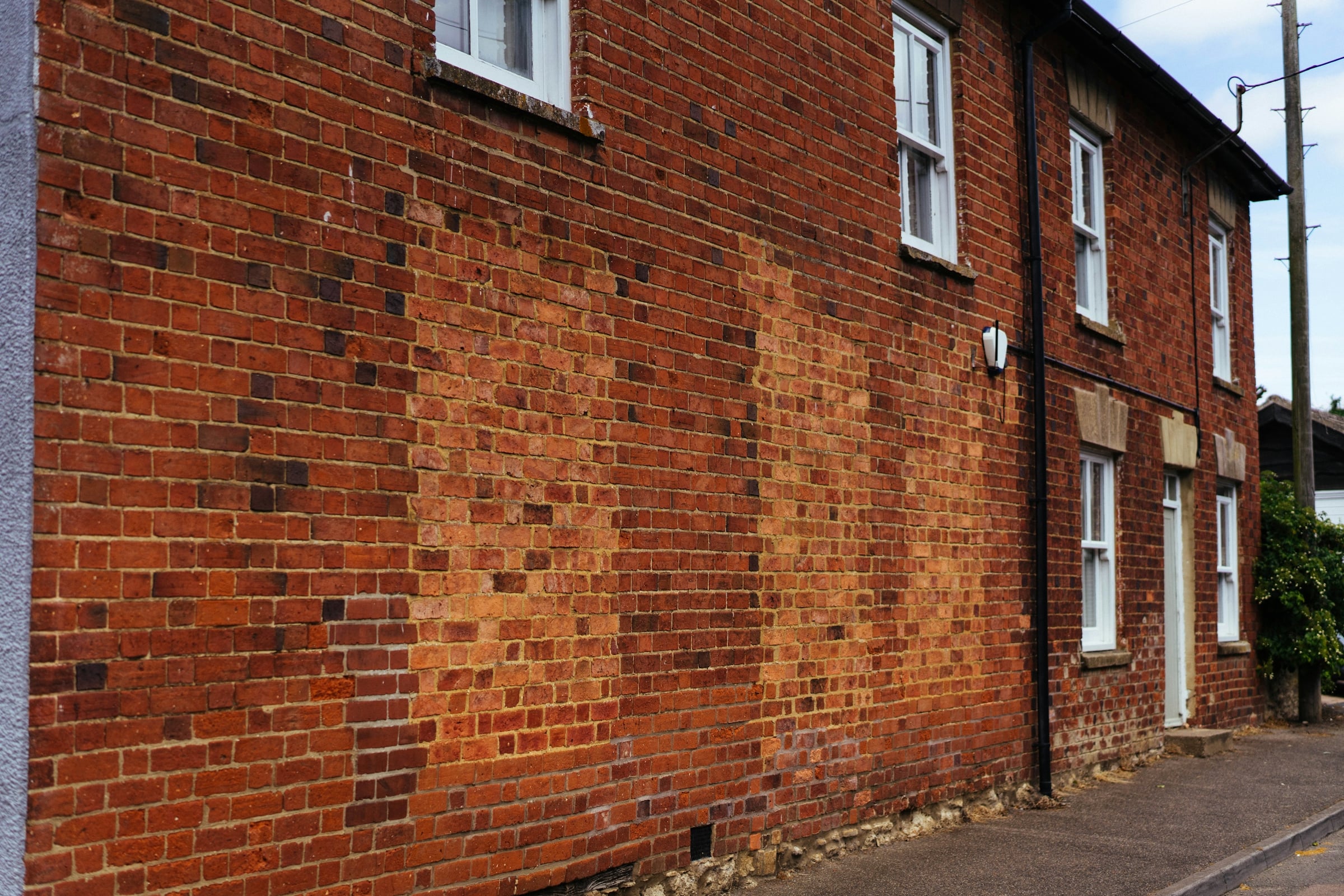 Red brick exterior wall with lighter patched brickwork where an older opening was filled in