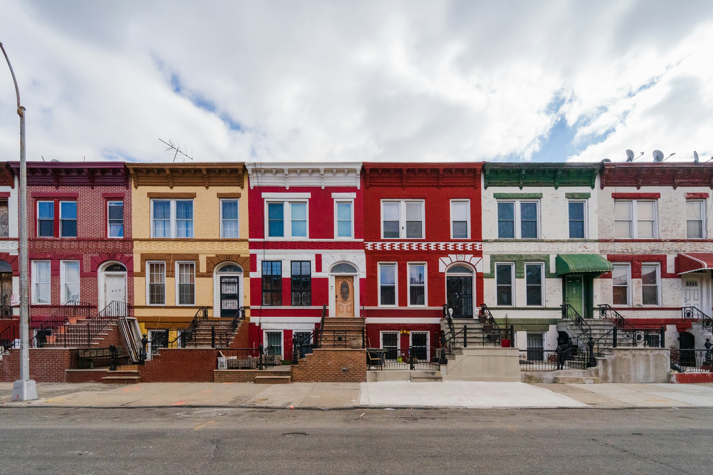 A terrace of narrow row houses painted in different bright colours along a city block.