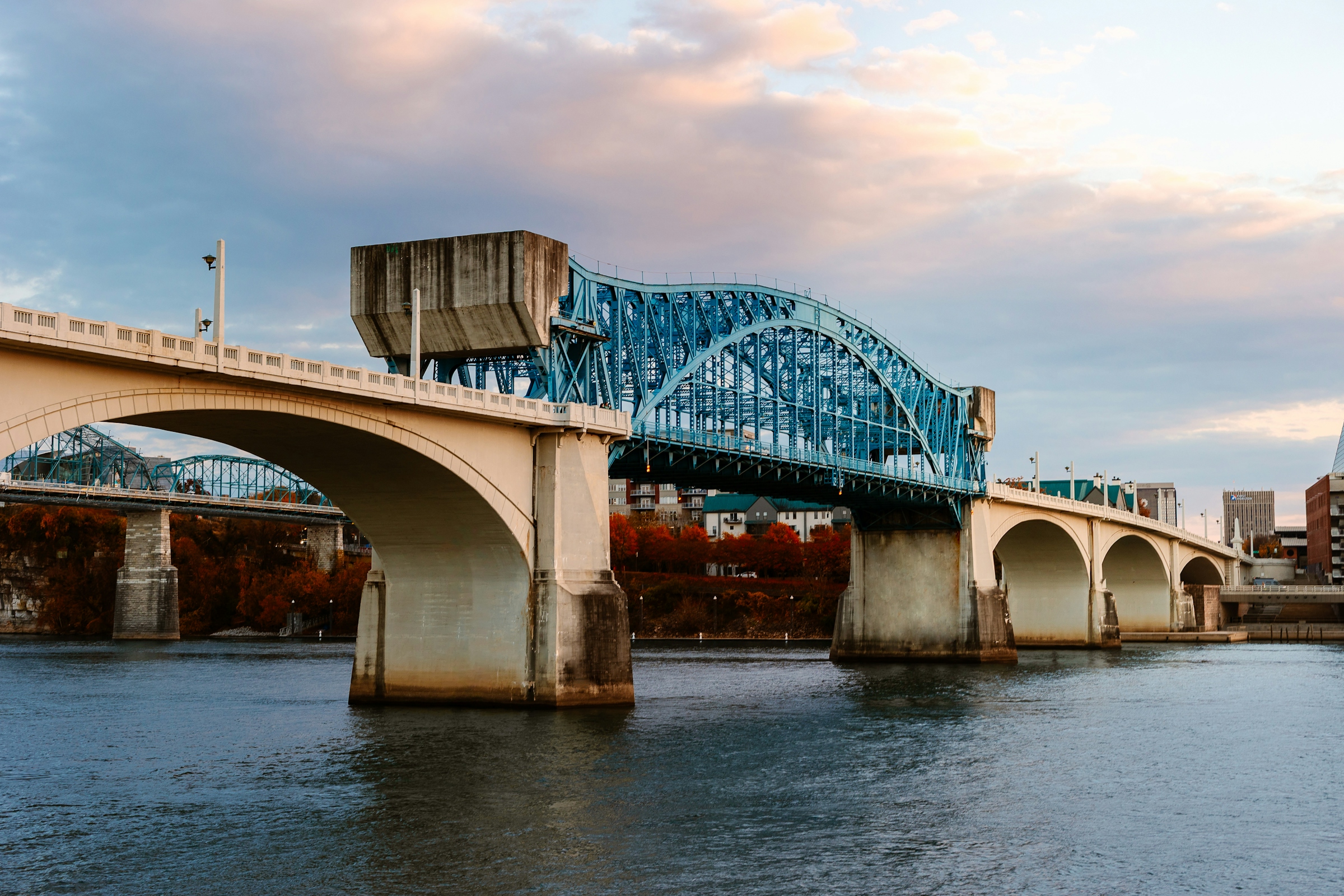 A wide concrete arch bridge carrying a roadway across a river