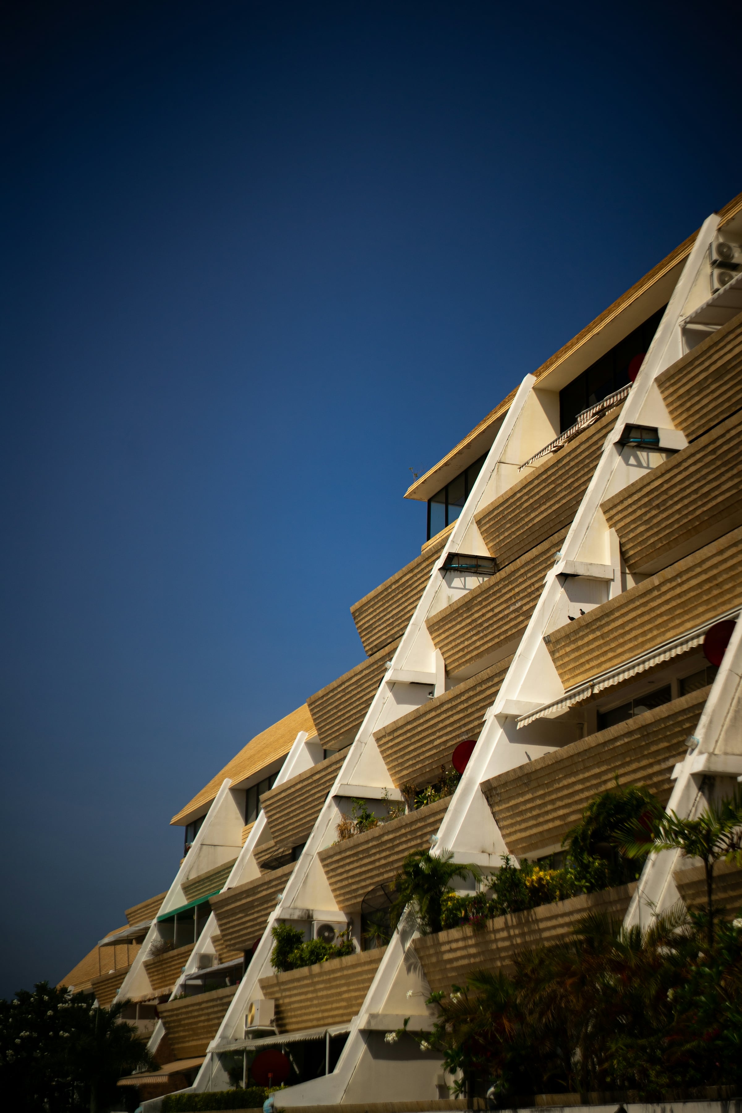 Angled view of a modern residential building's stacked concrete balconies against a deep blue sky