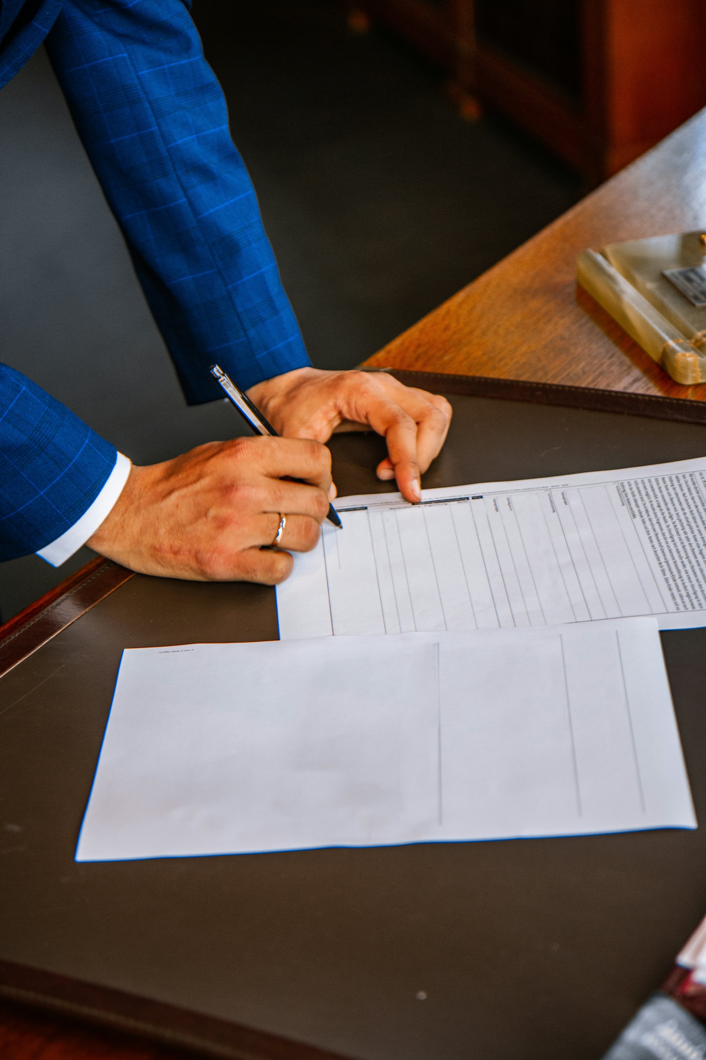 Two people reviewing and signing a printed contract across a wooden table