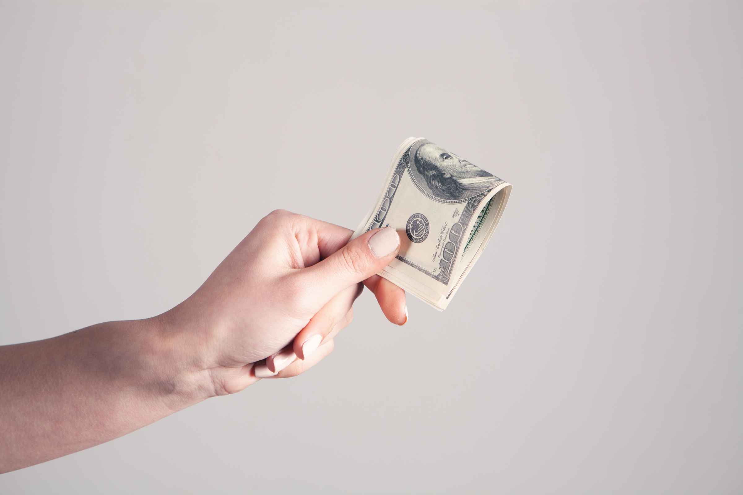 A hand counting out United States banknotes