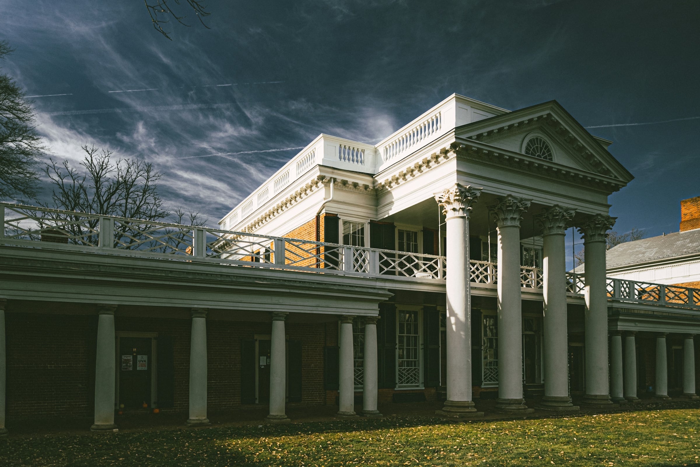 A white-columned historic Virginia house with a long veranda under a dramatic evening sky