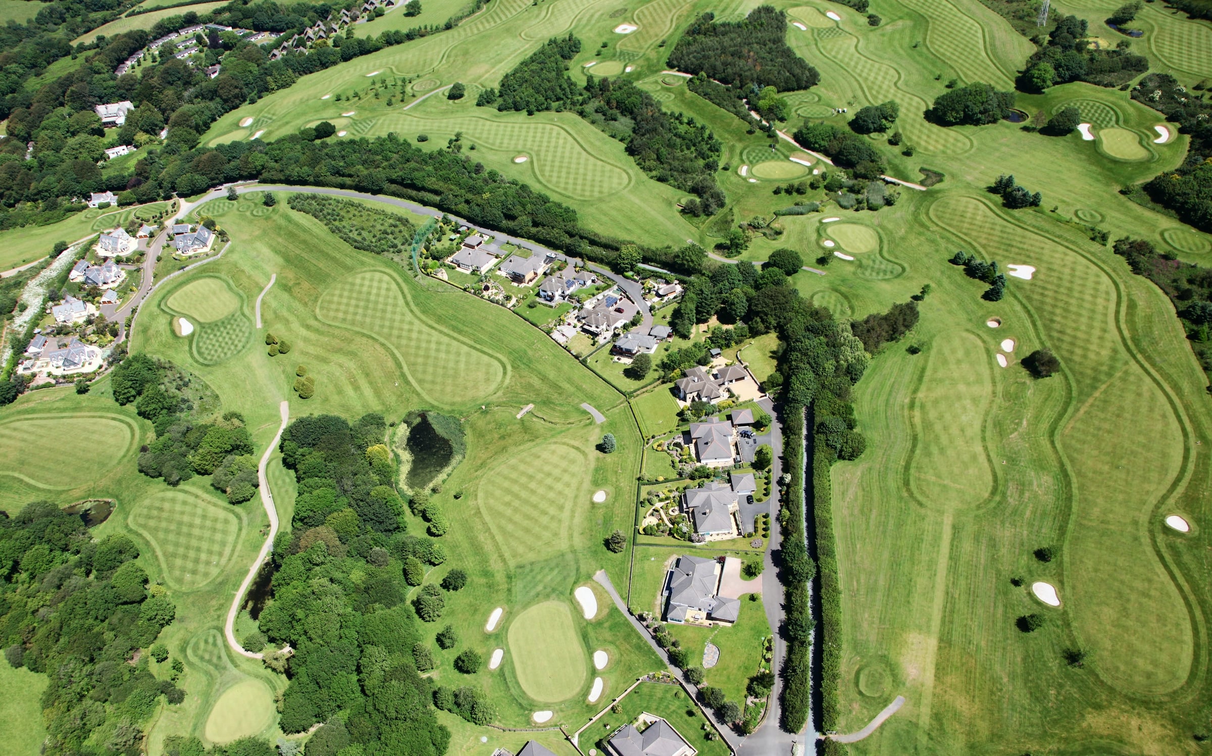 Aerial view of a golf course showing fairways and sand bunkers with houses backing directly onto the greens