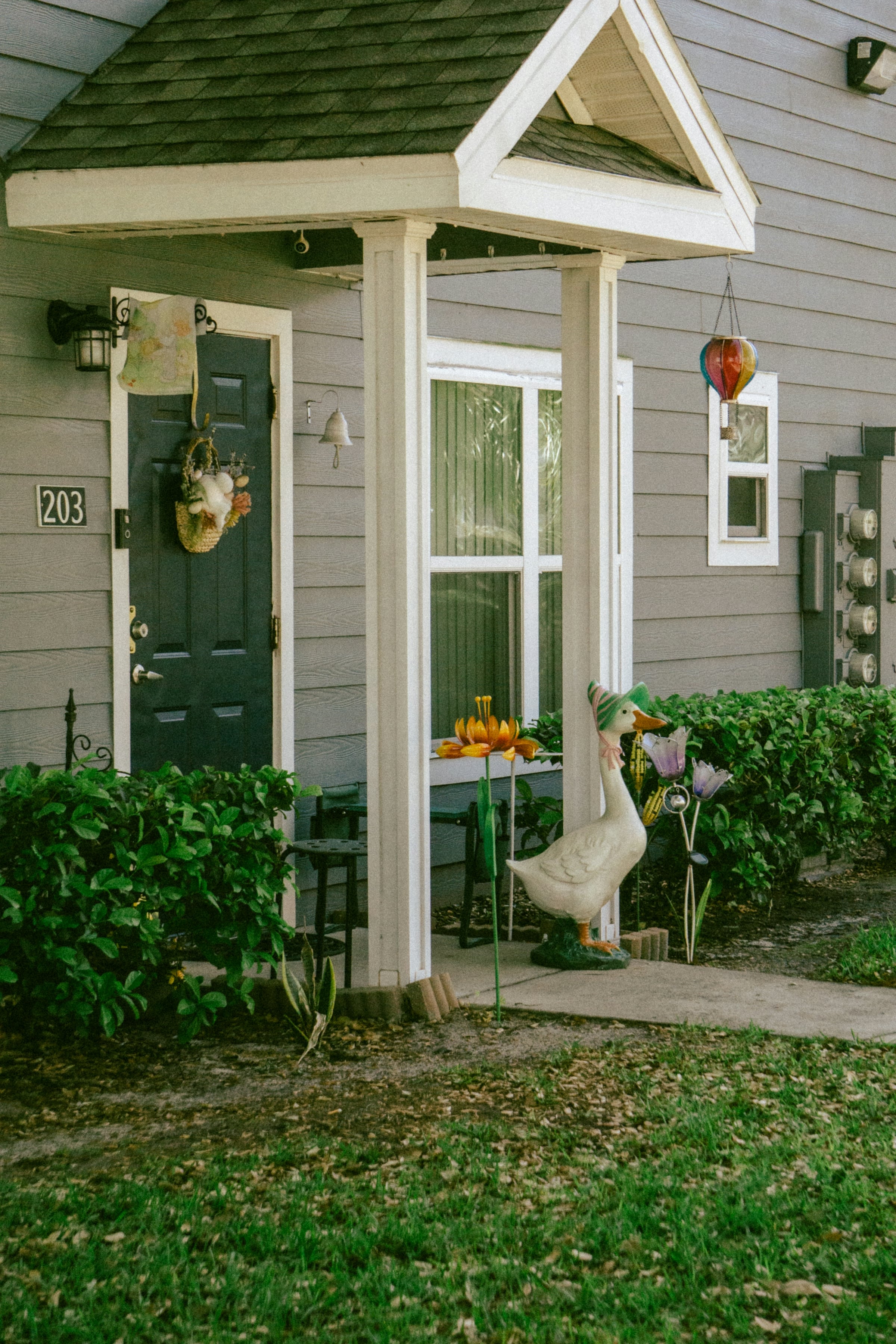 A green front door with an autumn wreath and pumpkins arranged on the step beside it
