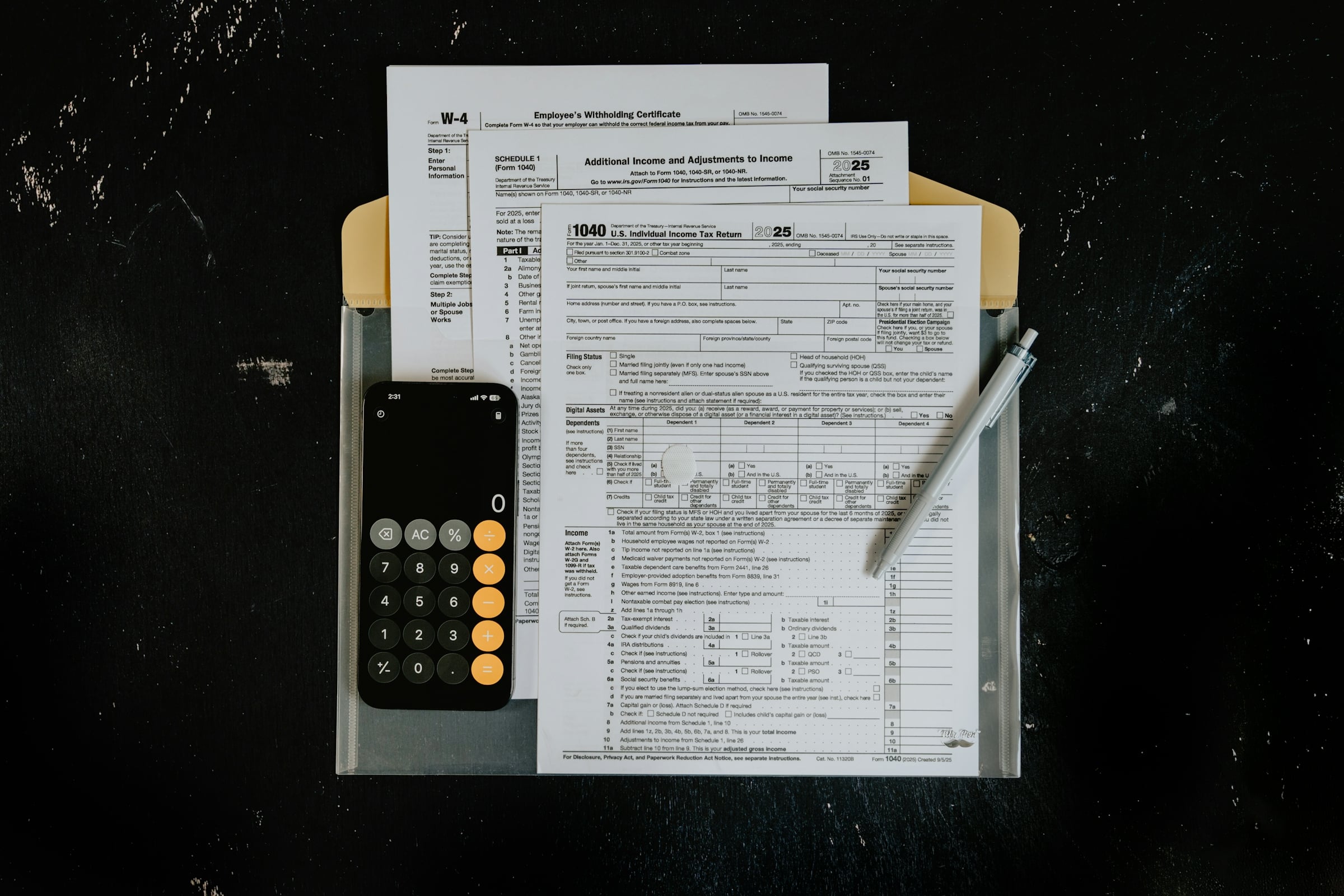 Printed tax forms in a manila folder beside a calculator and a pen on a dark desk