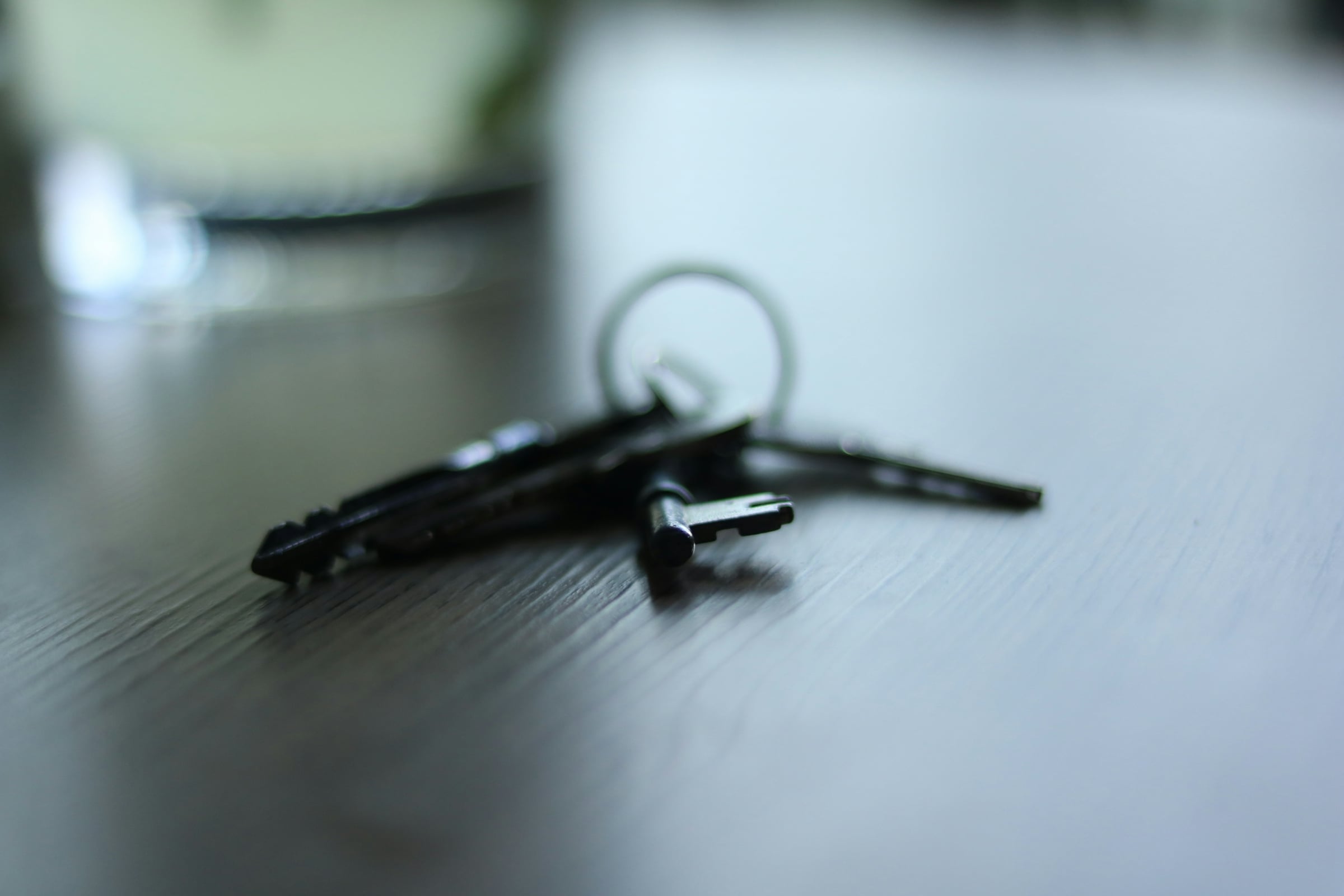 A set of house keys on a ring lying on a dark wooden table.