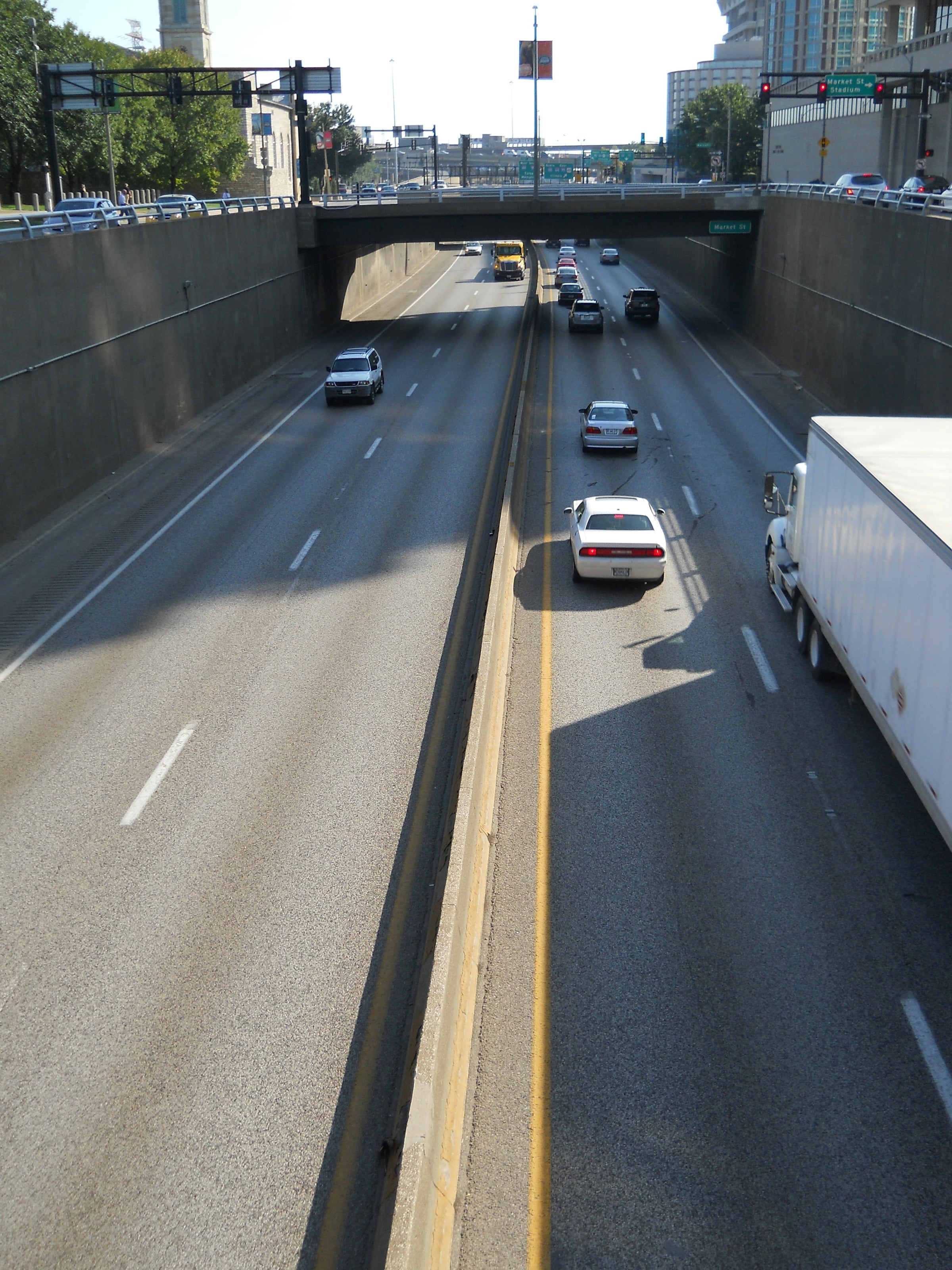 Cars and a box truck spread across the lanes of a divided interstate highway on a clear day, seen from an overpass.