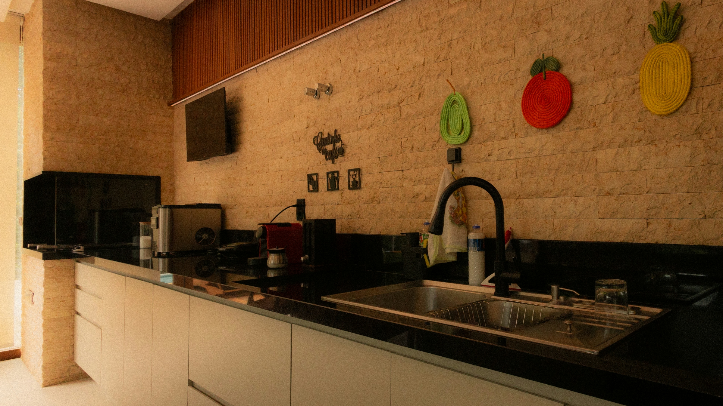 A kitchen with an exposed brick wall, dark counters and pans hanging above the worktop