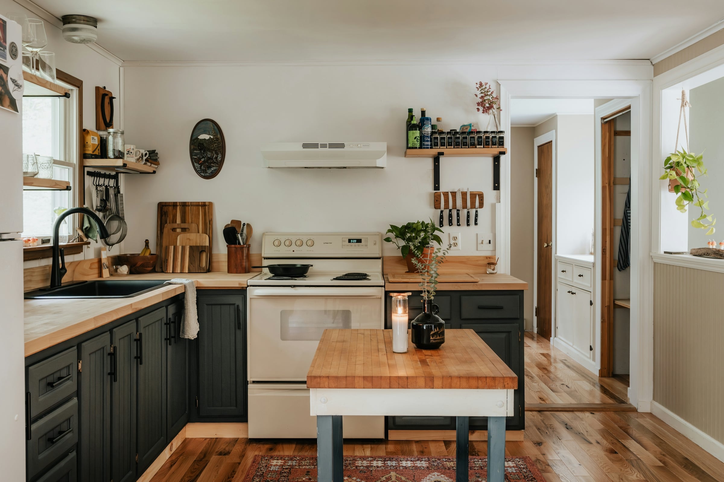 A kitchen with pale green lower cabinets, white uppers and a butcher block island