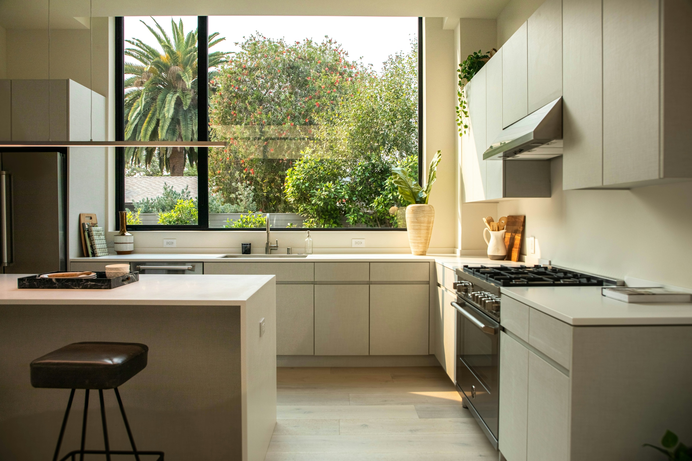 A kitchen island facing a window with a gas range set into the run of cabinets behind