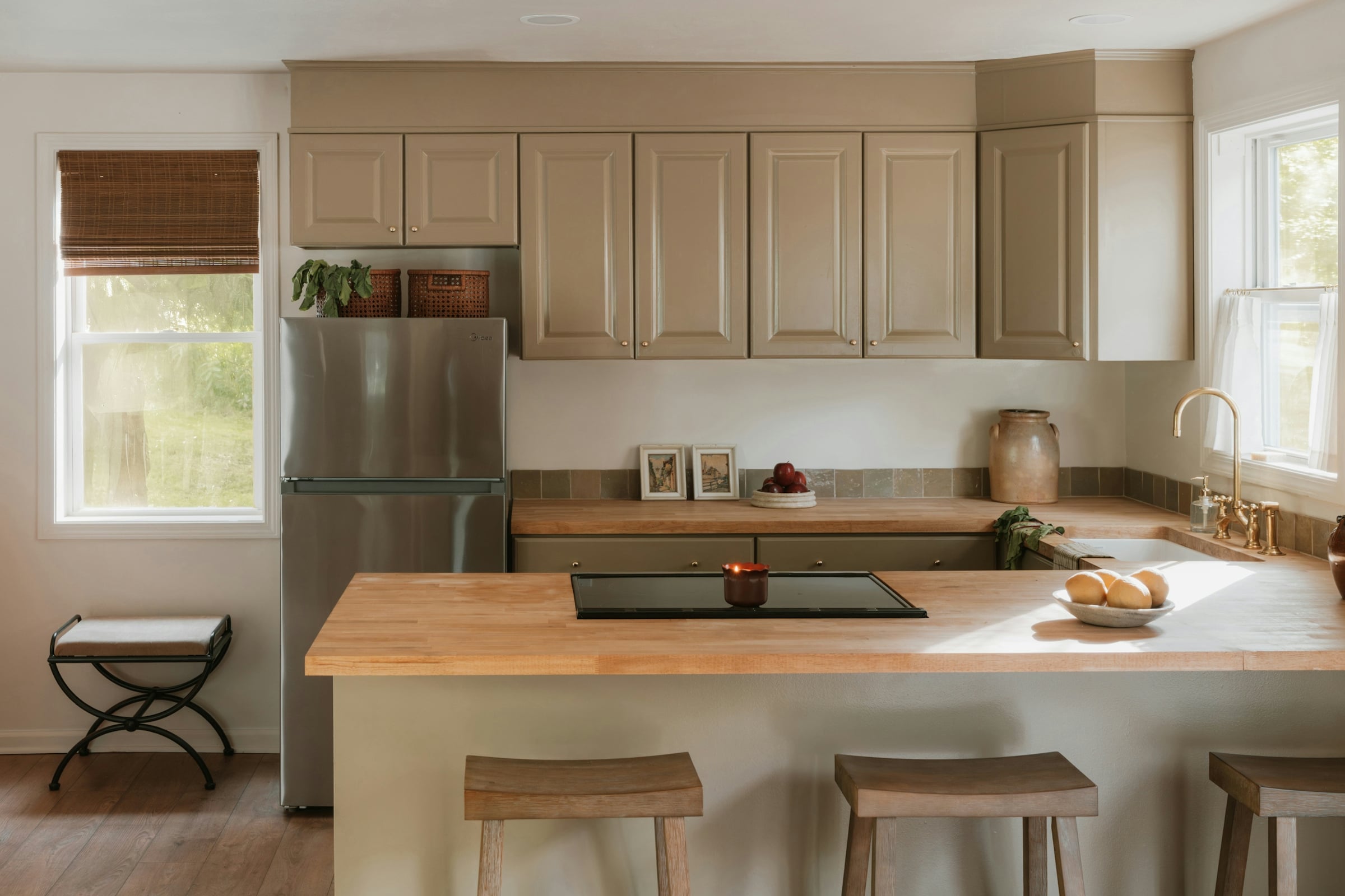 A light wood kitchen with a stainless steel refrigerator and a run of upper cabinets