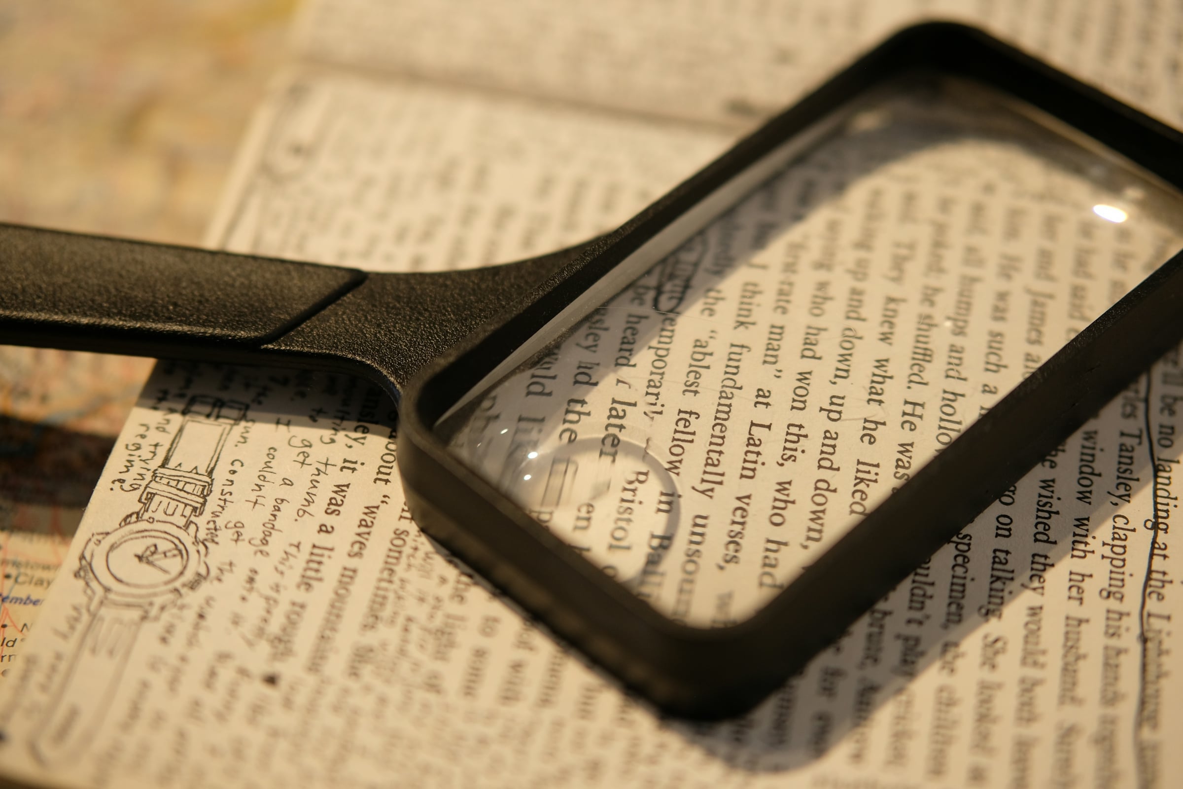 A magnifying glass resting on a page of dense printed text, as if reading fine print