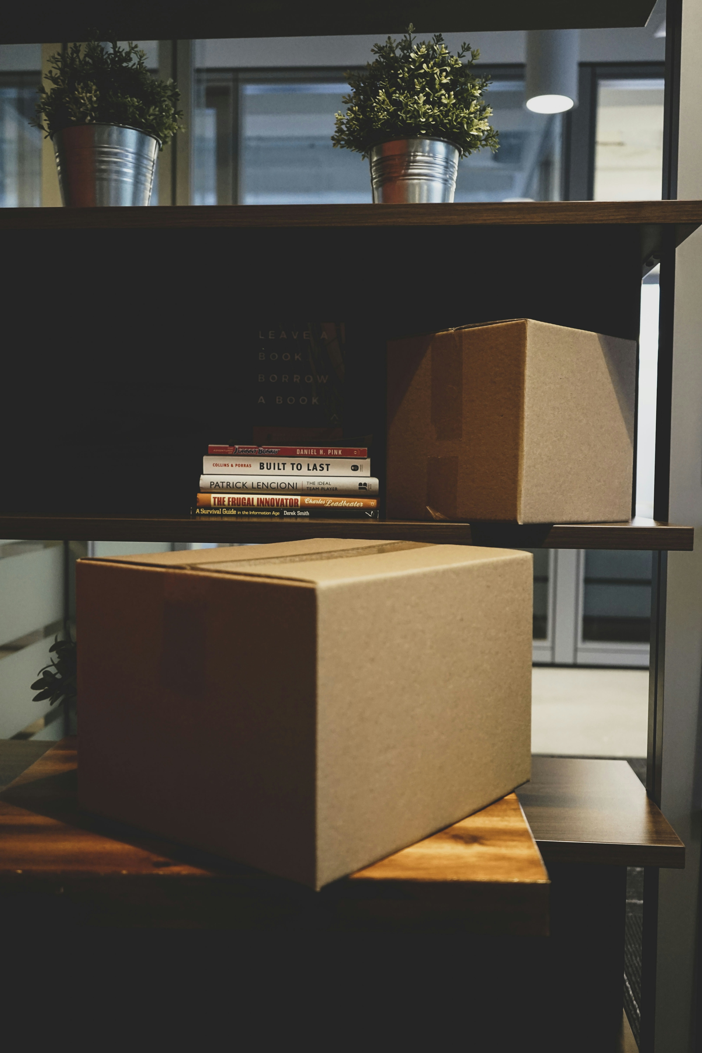 A sealed cardboard moving box with a stack of books resting on top of it
