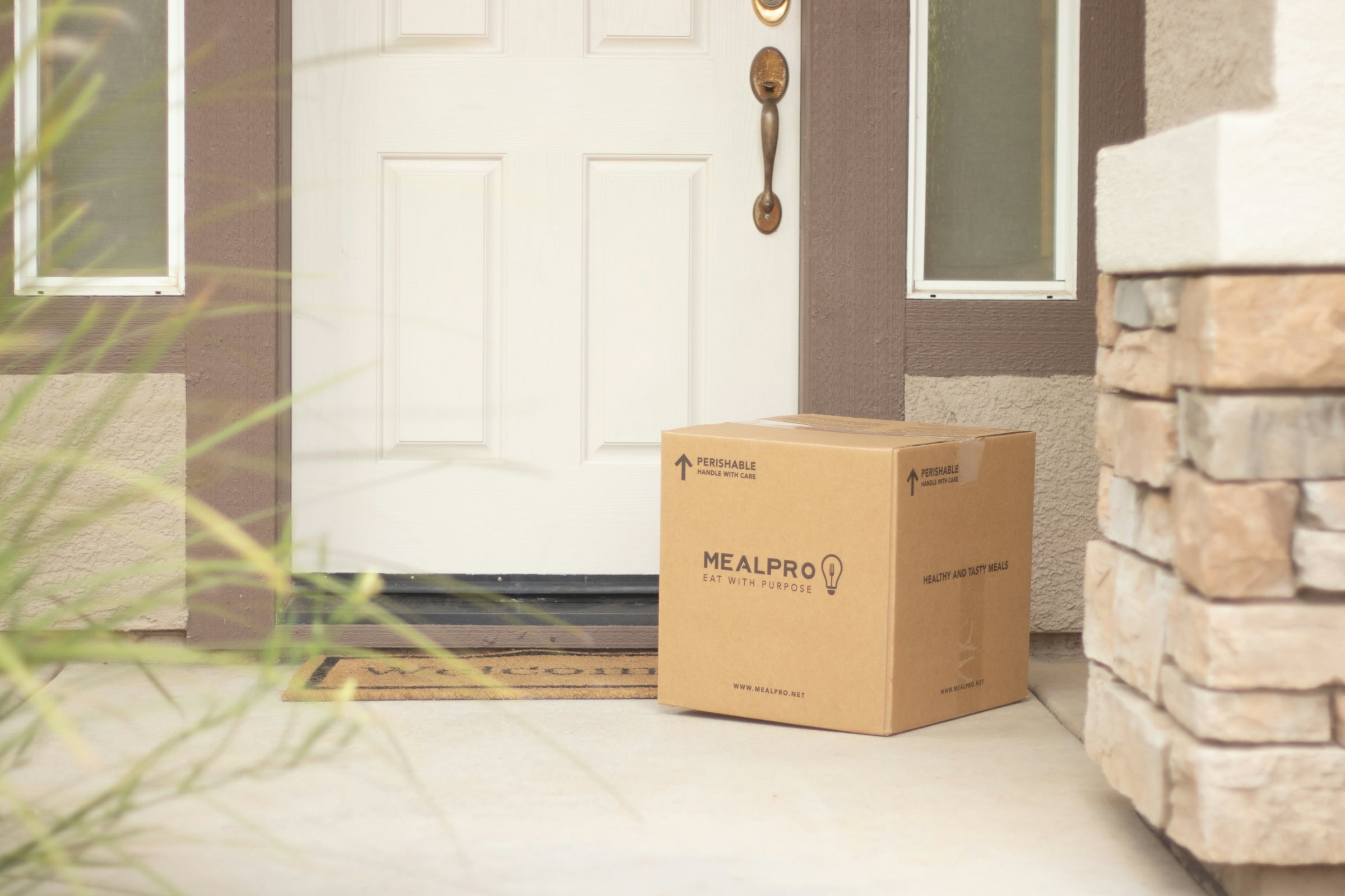 A single cardboard moving box on the floor beside an open interior door and a brick wall