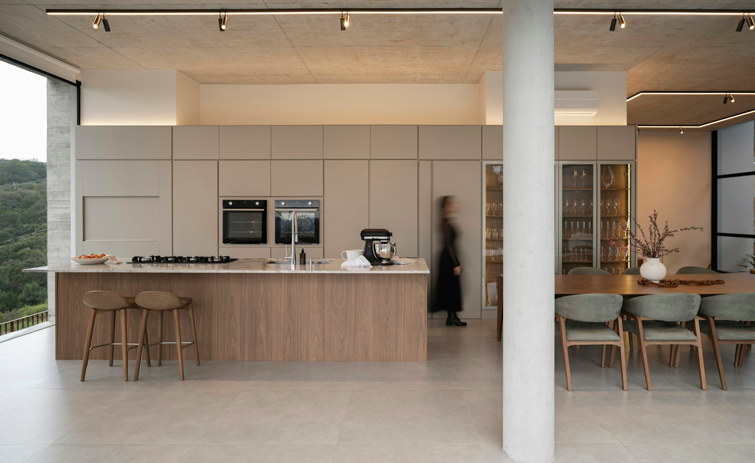 A large open plan kitchen with a long island, bar stools and painted structural columns