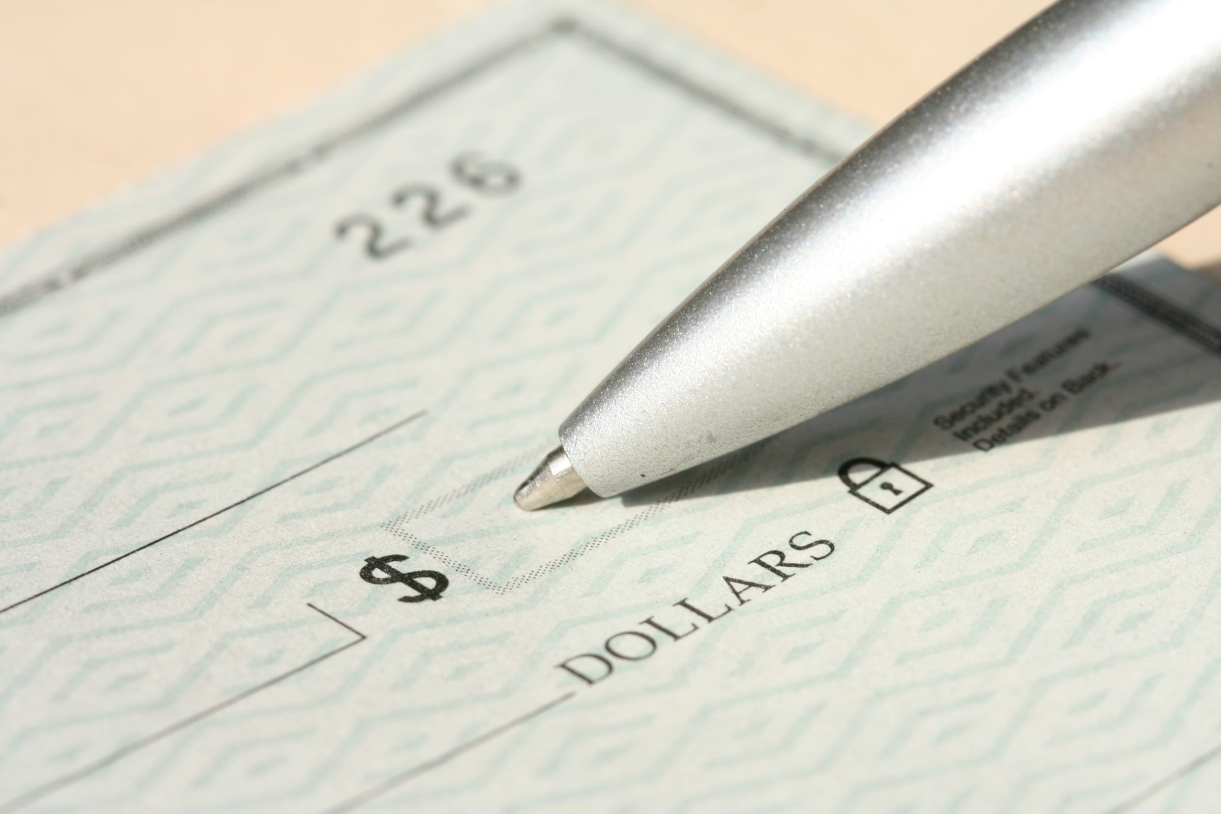 A pen poised over a blank check, ready to write