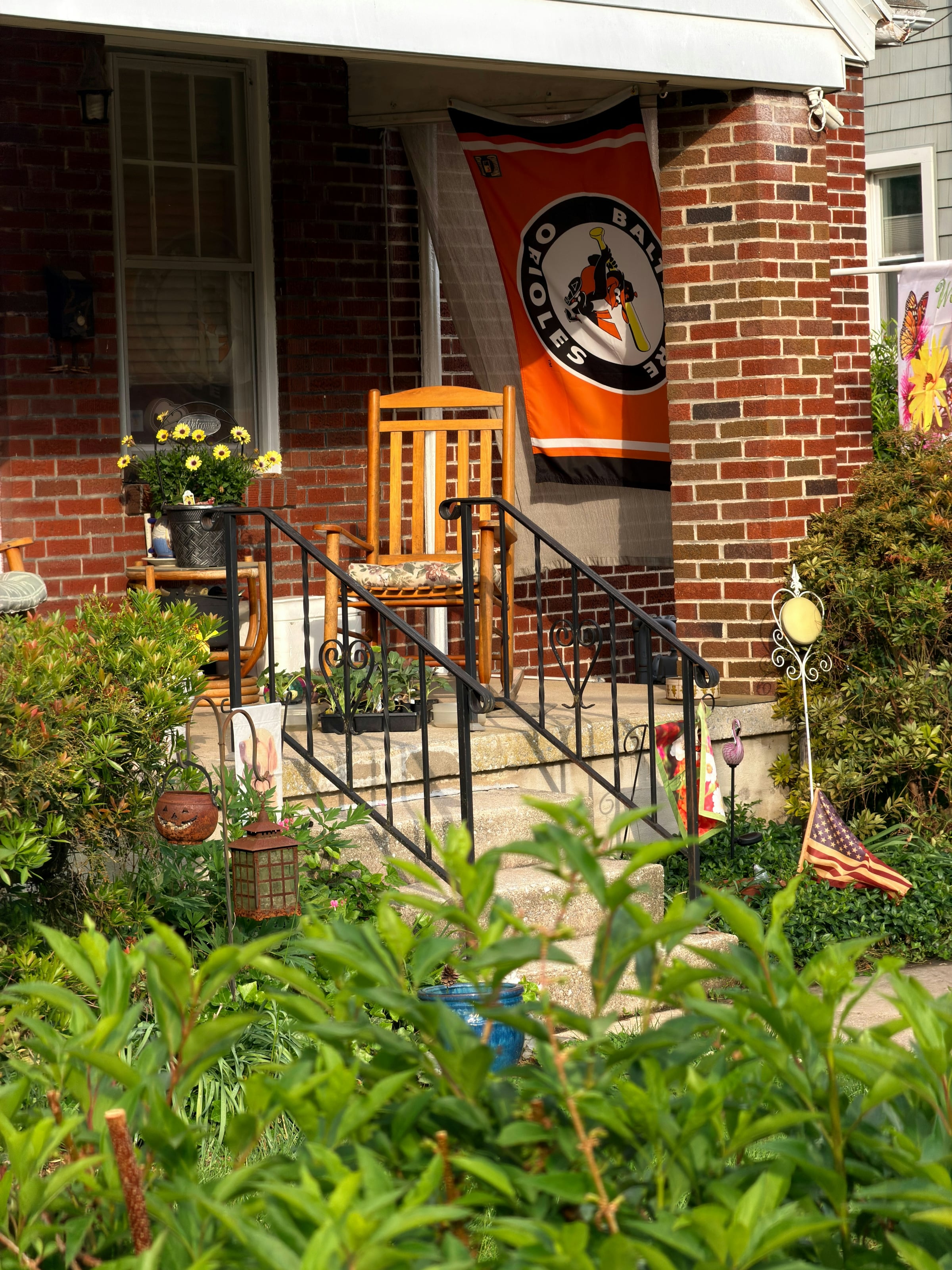 Wooden porch steps with black railings leading up to the door of a red brick house