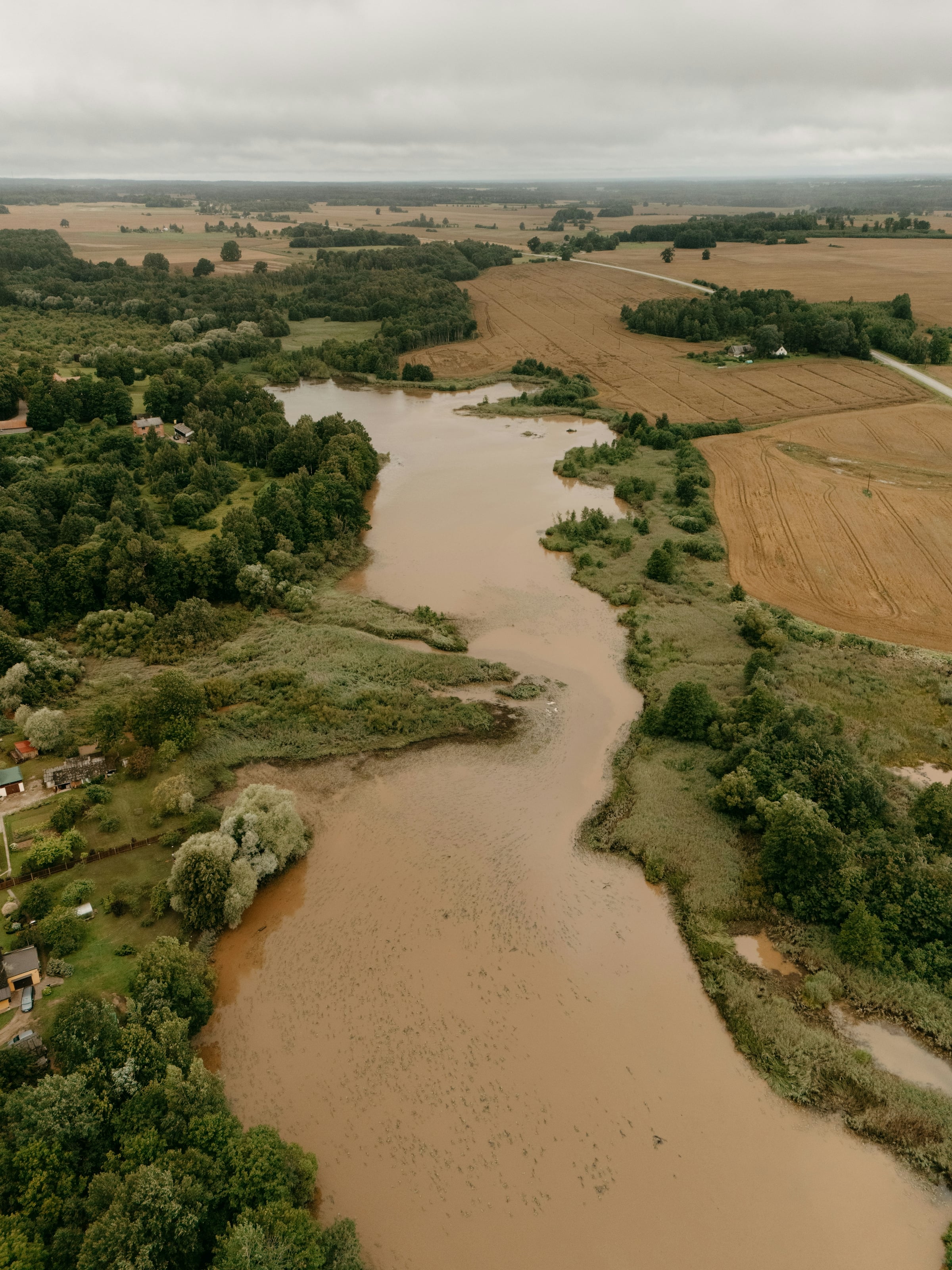 A brown river winding through low farmland, seen from the air