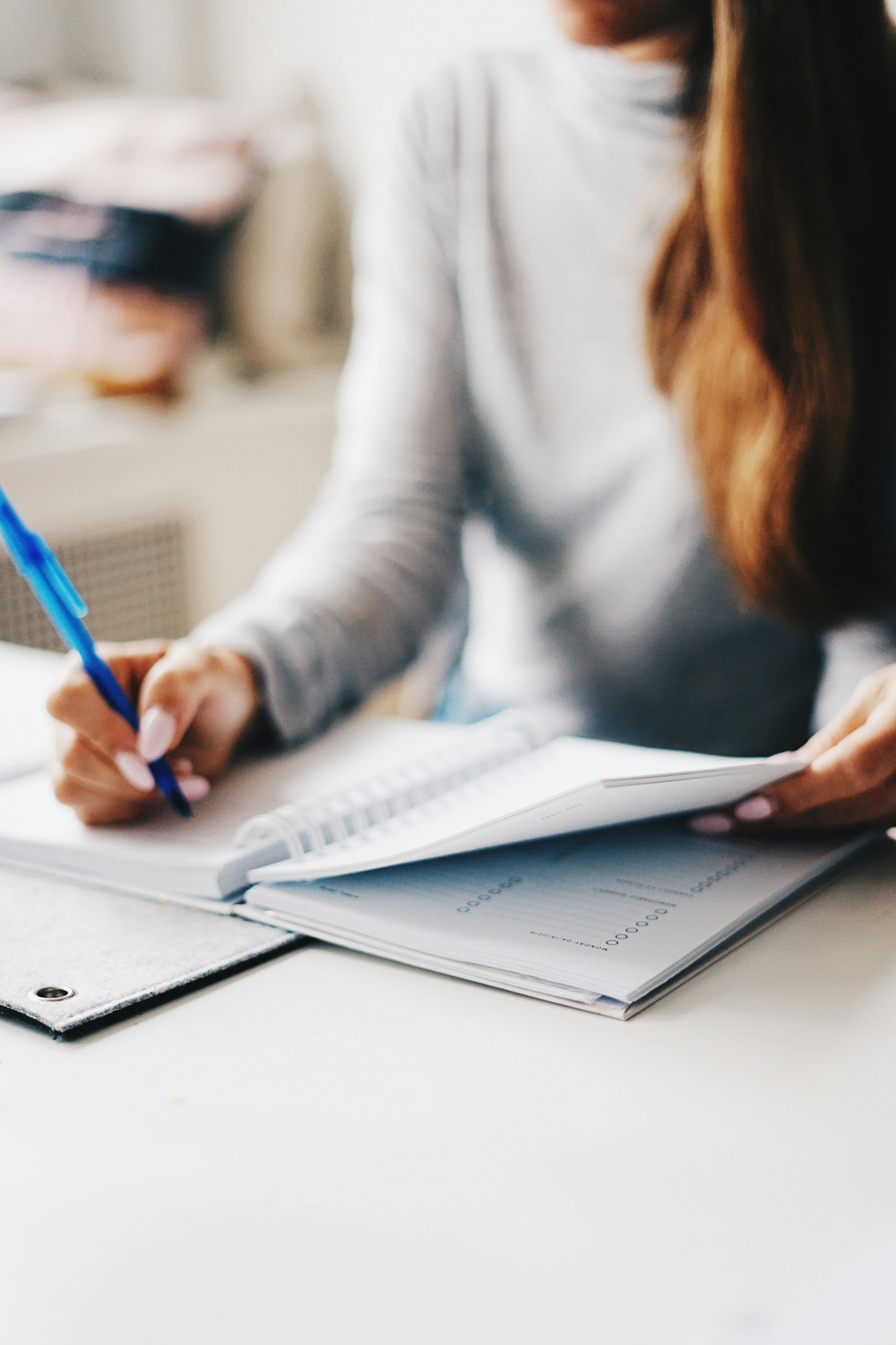 Hand signing a document with a blue pen