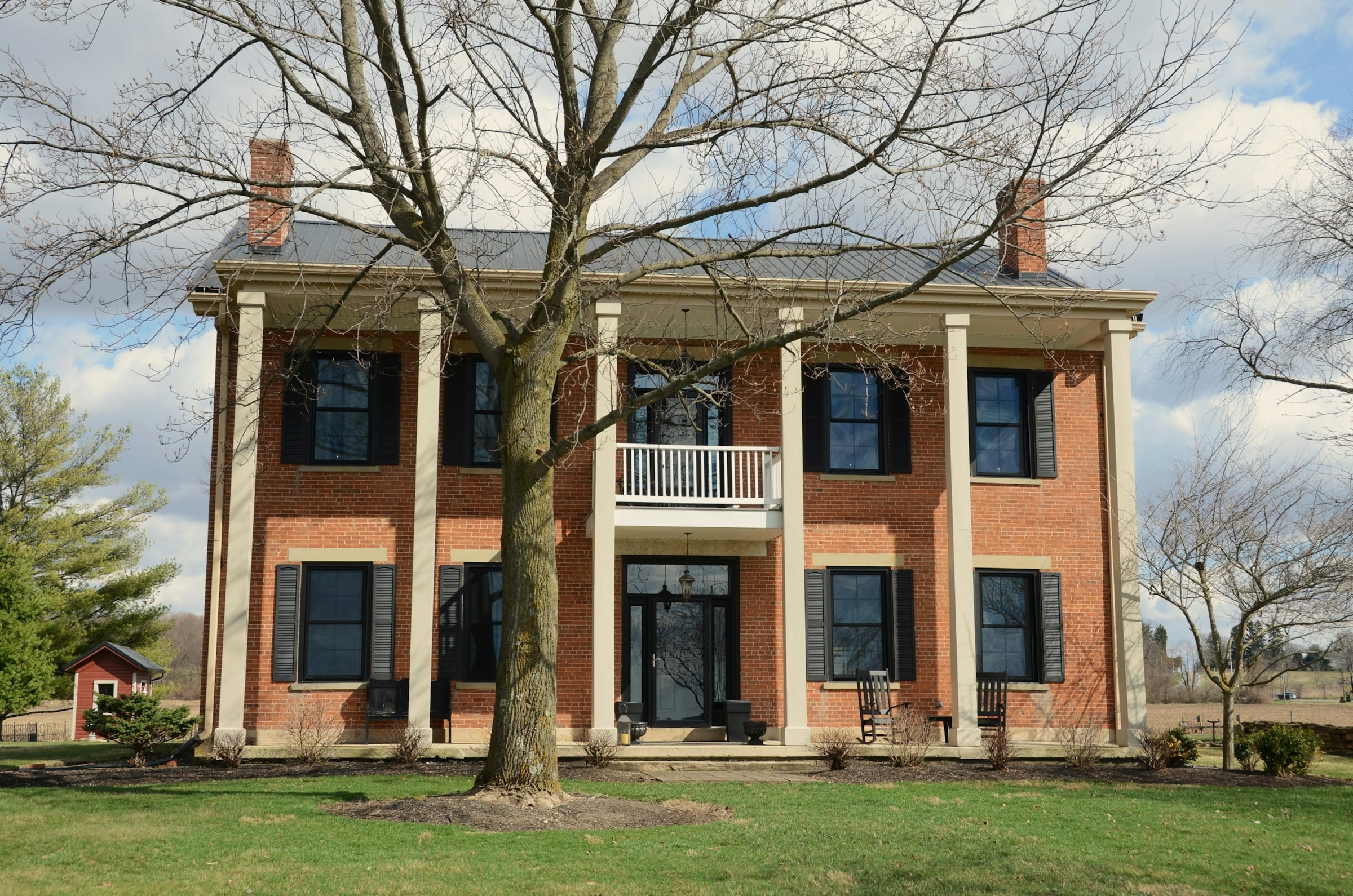 A large stucco house with two storeys of white columns across its front elevation