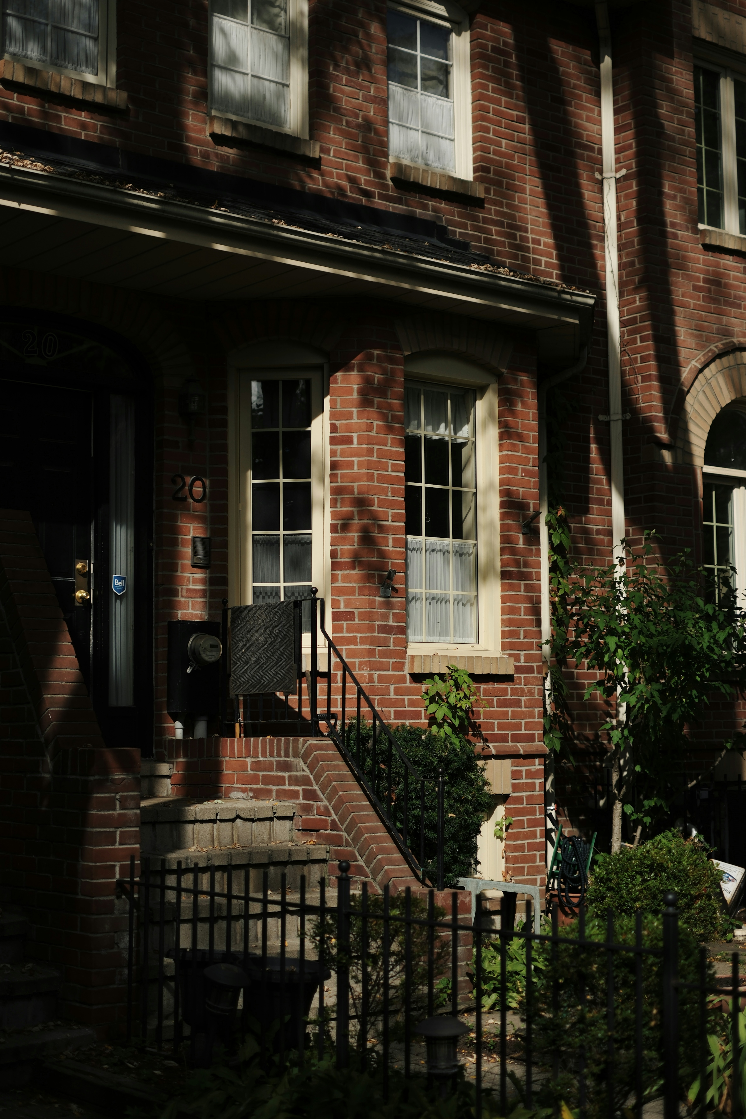 The brick frontage of a townhouse with a dark panelled door and a tall sash window