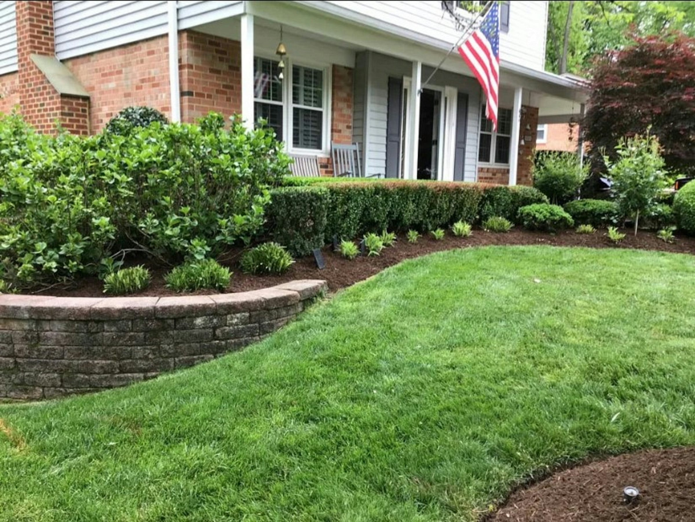 Trimmed hedge and lawn along a brick walkway