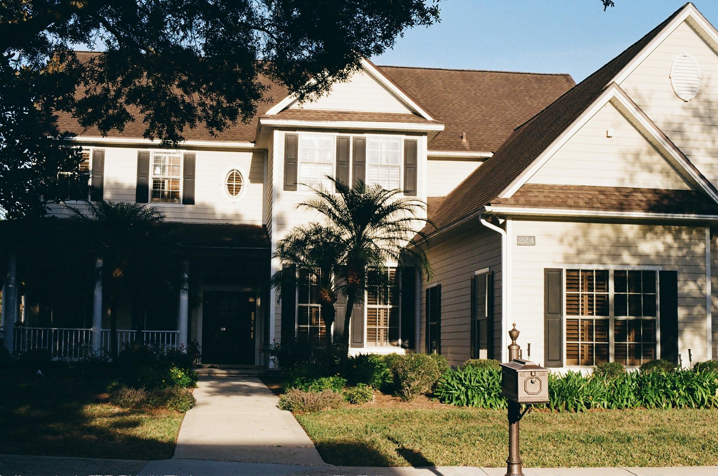 A large two-story house with a covered front porch seen from the street