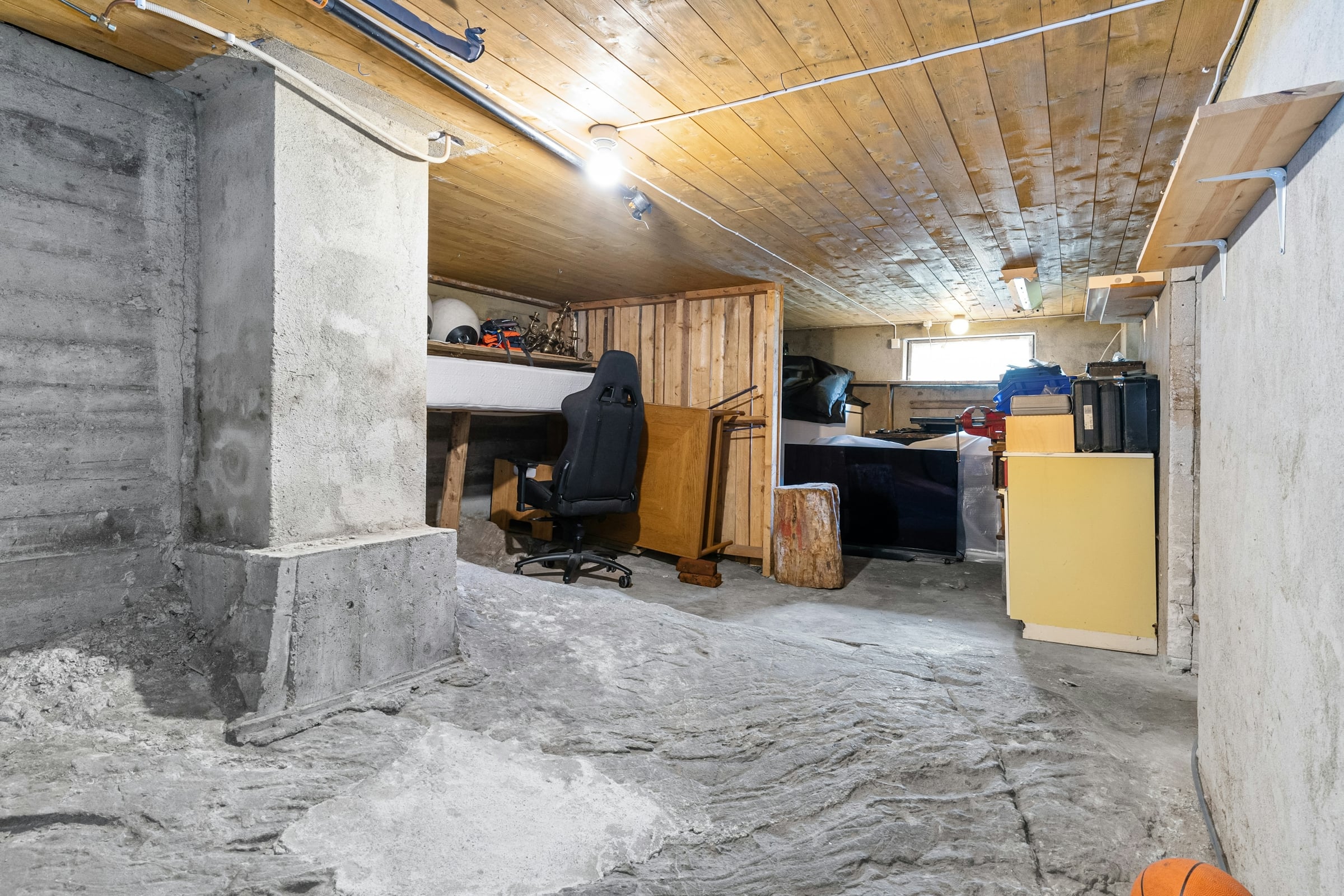Unfinished basement level with bare concrete, framing lumber and repair work underway