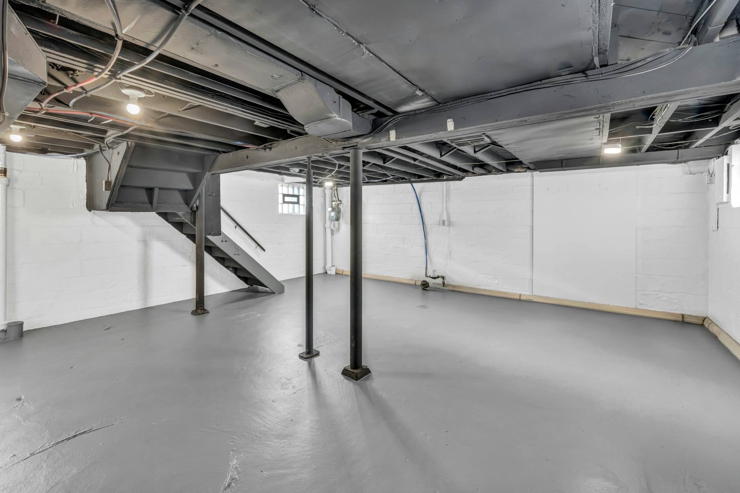An empty unfinished basement with painted walls and steel support columns