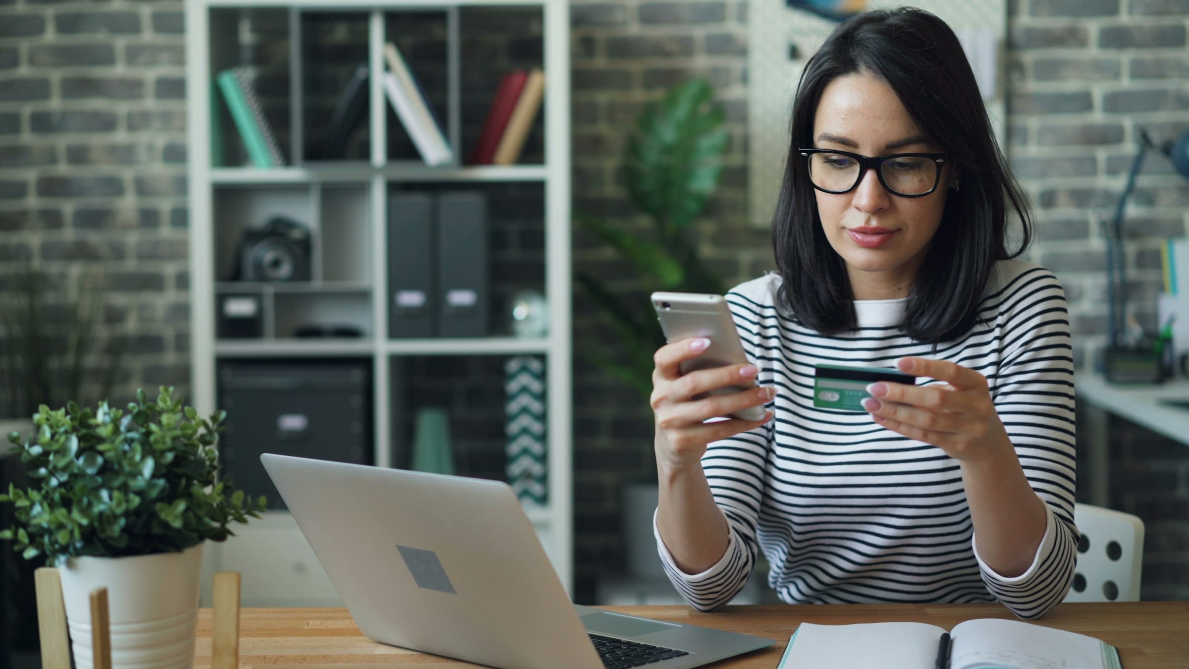 A woman seated at a table checking her phone
