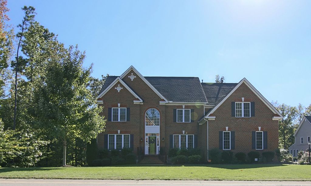 A two-story brick colonial with an arched entry window on a wooded lot in Salisbury, Midlothian, Virginia
