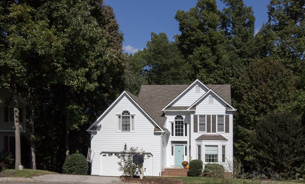 A white two-story colonial under mature hardwoods in Woodlake, Chesterfield County, Virginia