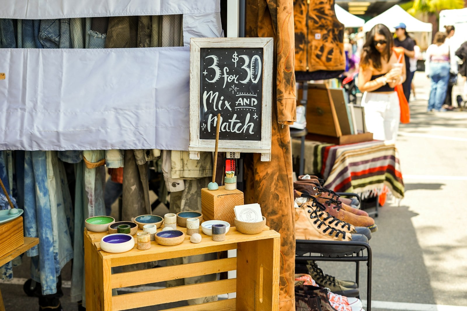 Craft market stall with handmade pottery, textiles and a chalkboard sign