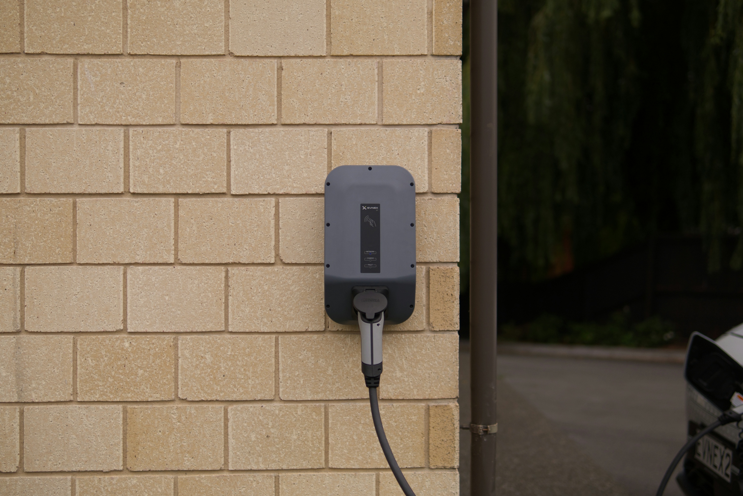 Wall-mounted home electric vehicle charger with cable on an exterior brick wall
