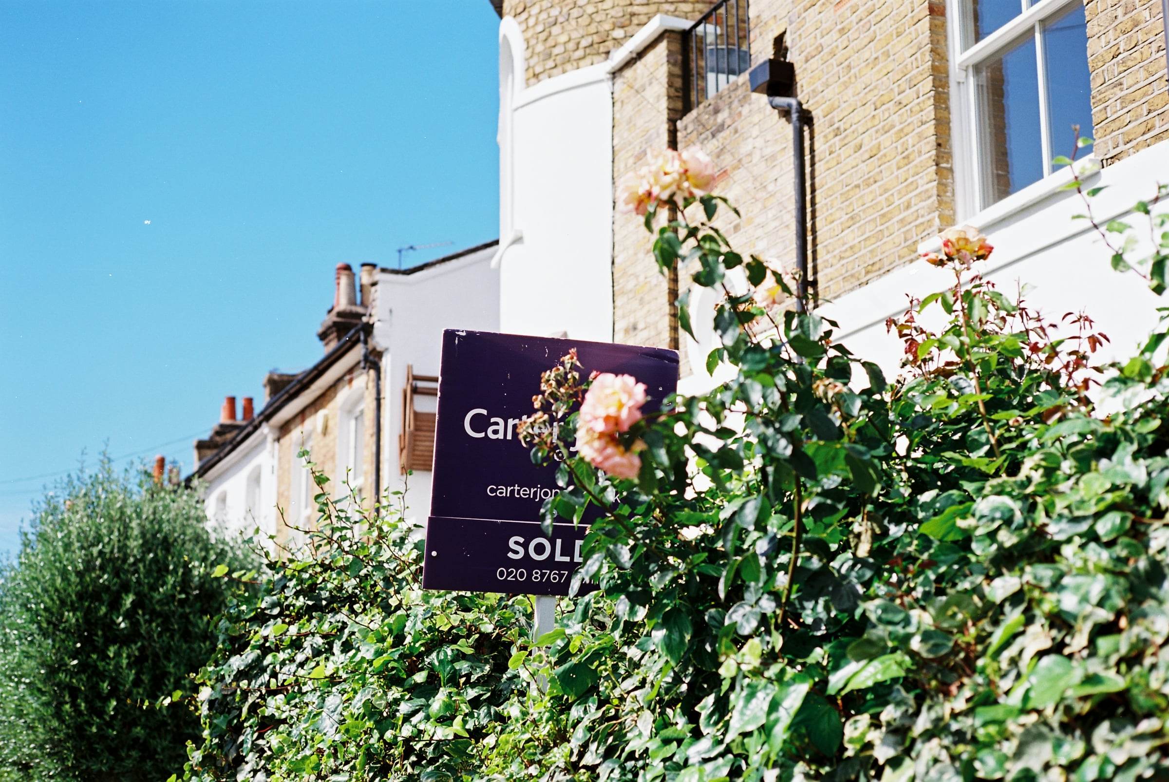 A sold sign and roses in front of a house, representing a completed home sale