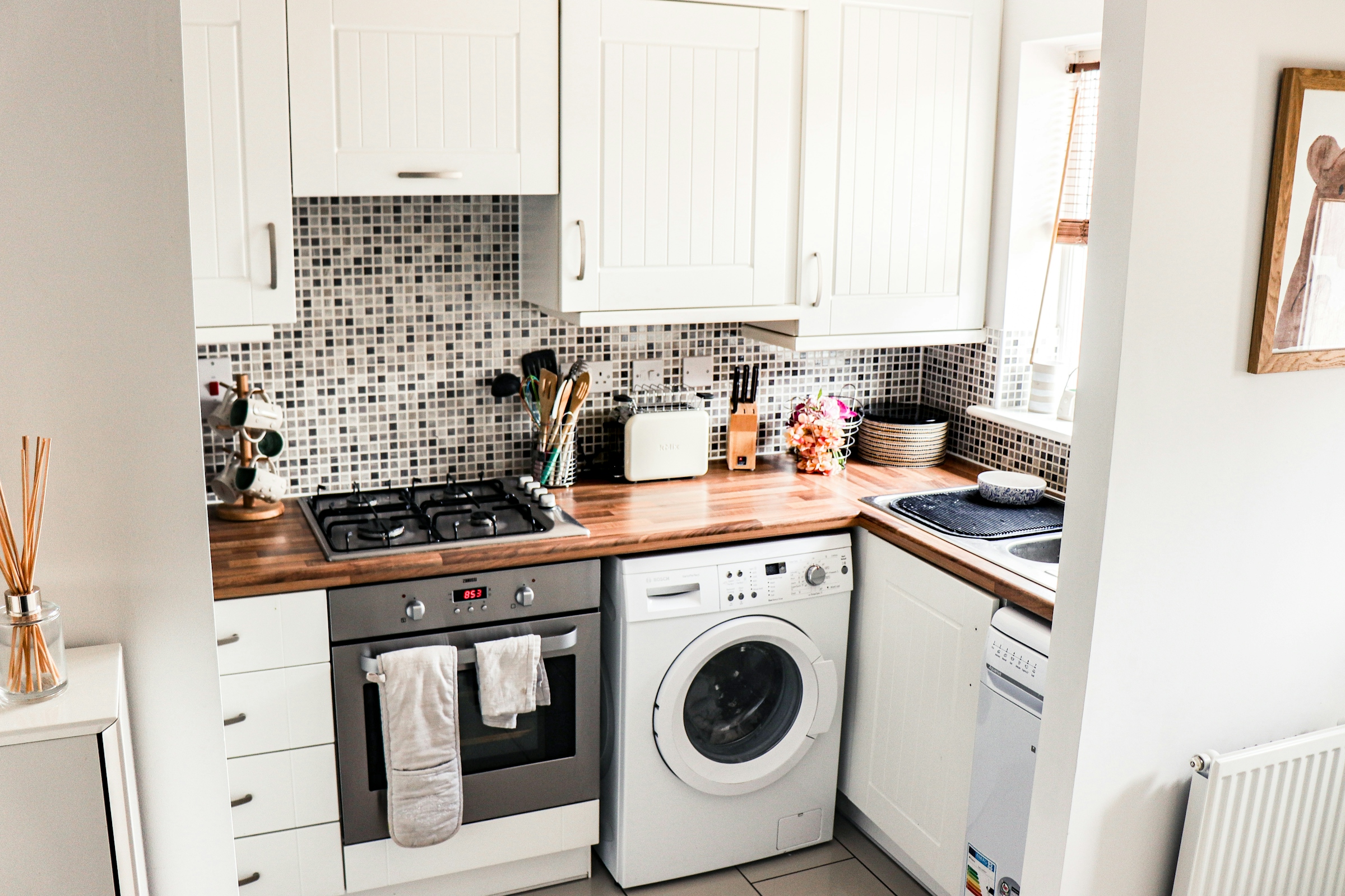 Home kitchen with a gas range, oven and front-load washing machine, the kind of appliances a home service contract may cover
