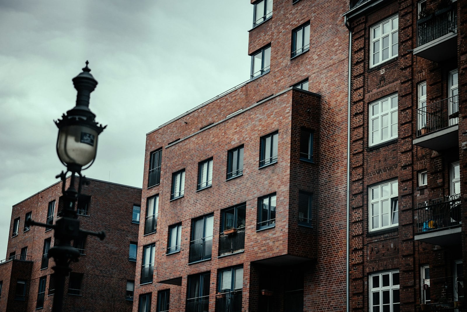 Brick apartment and commercial buildings with large windows beside an ornate street lamp
