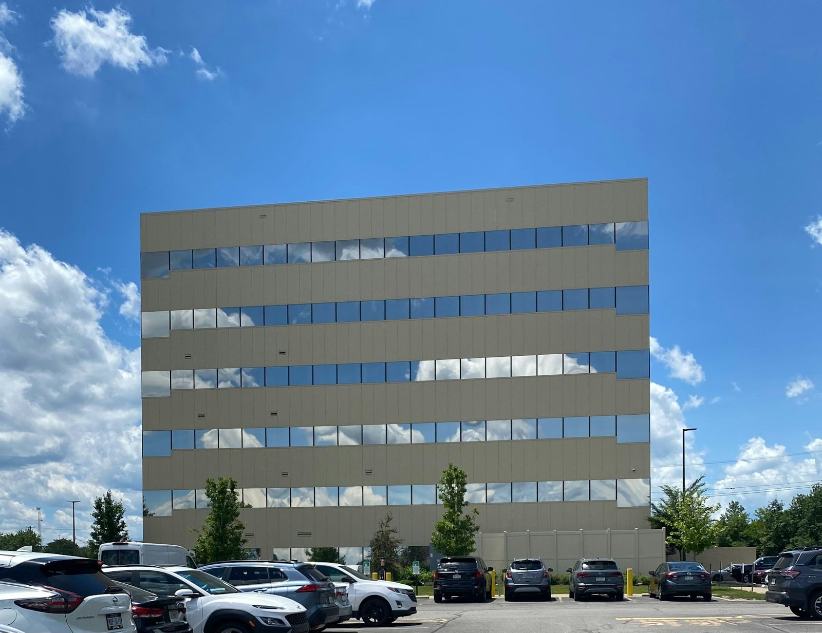 Modern multi-story office building with a glass facade against a blue sky