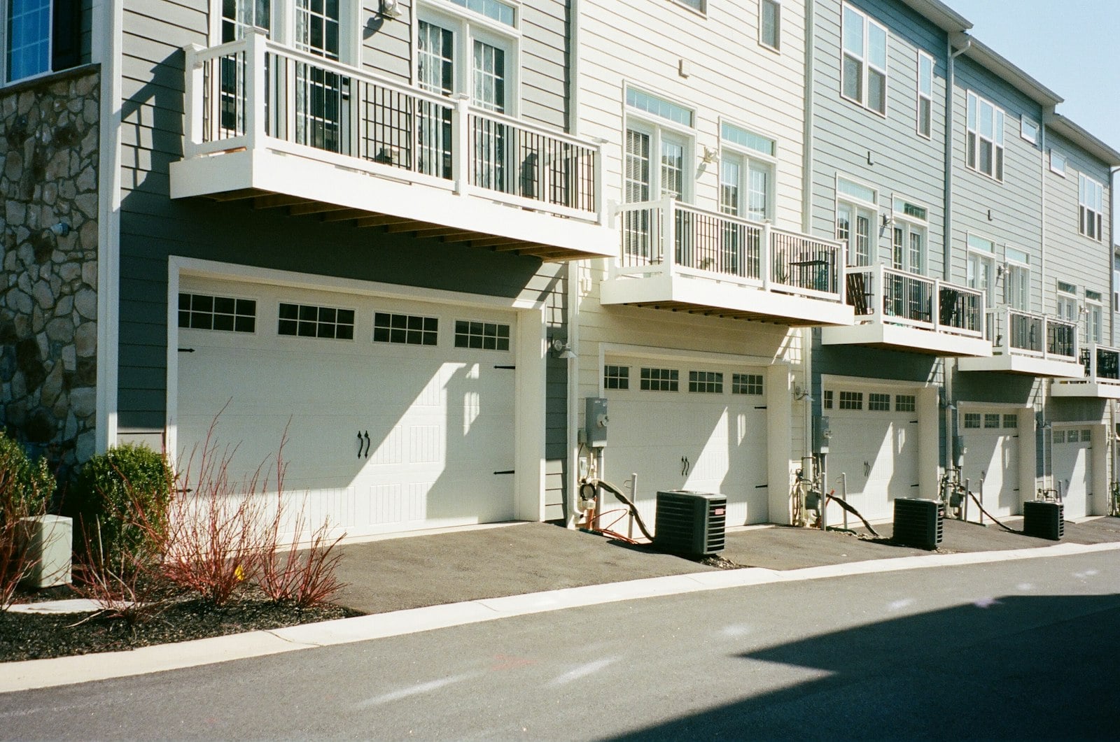 Row of modern three-story townhomes with attached garages and balconies