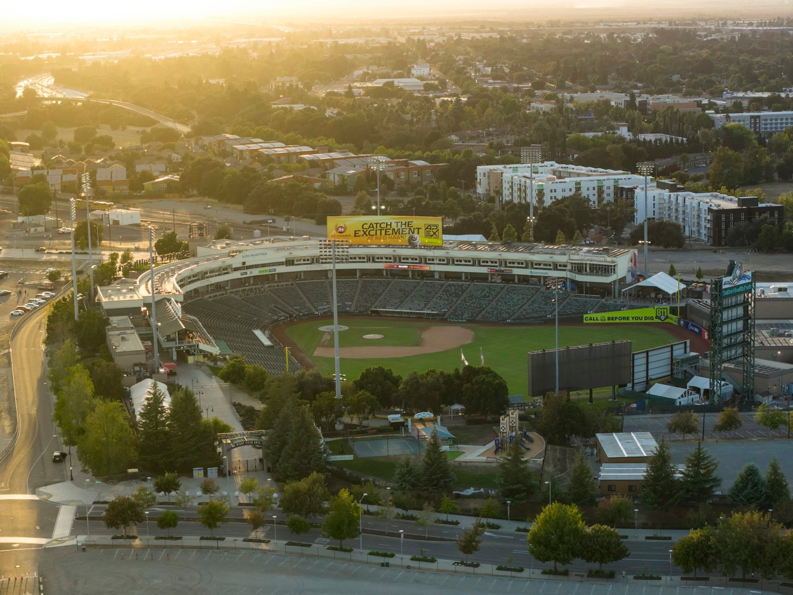 Aerial view of a minor league baseball stadium and the surrounding city blocks at sunset