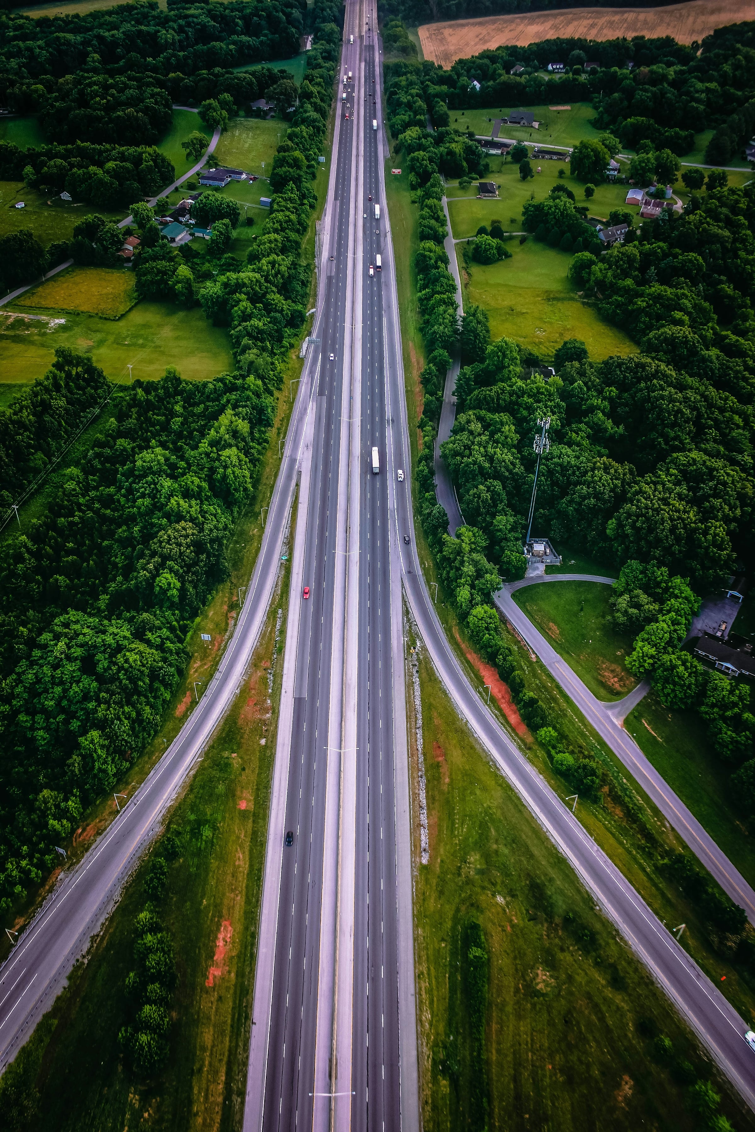 Aerial view of a divided highway with several lanes running through dense green forest