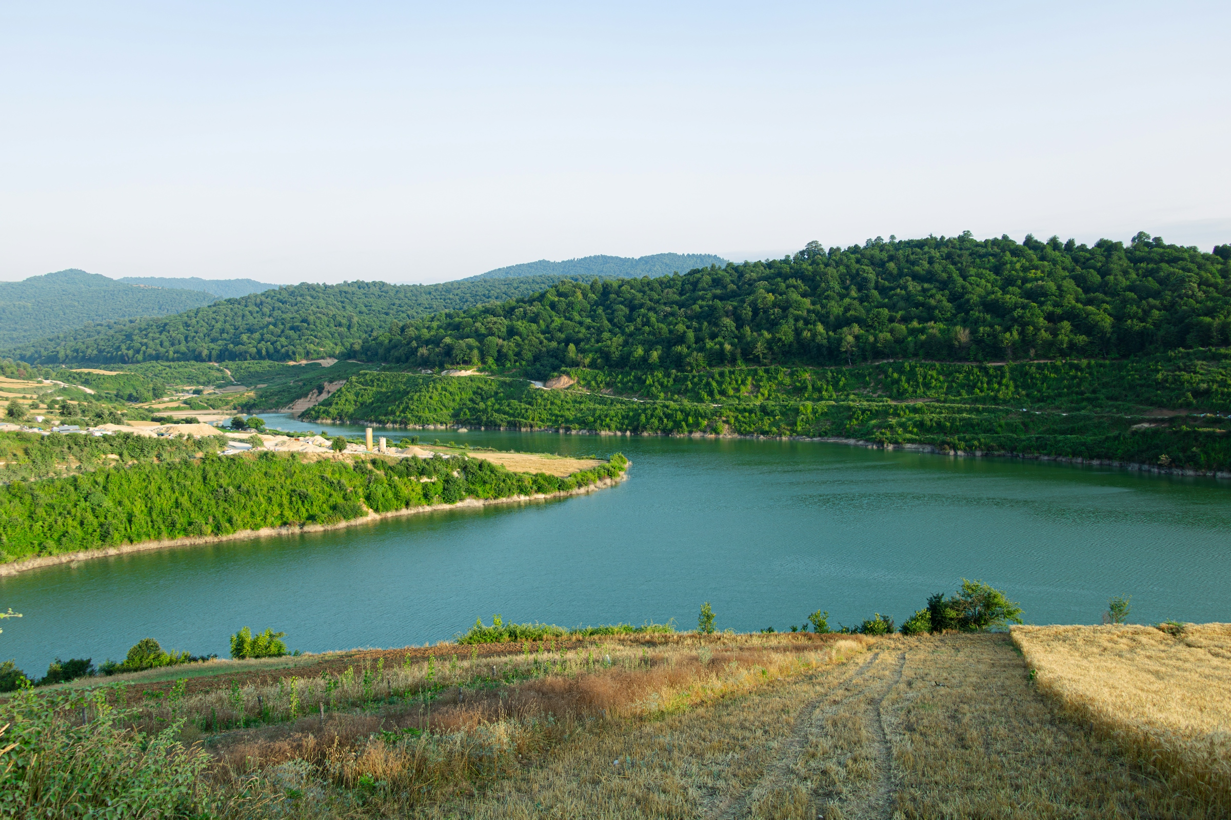 Wooded river bend under a clear sky, representing a river as the source of community drinking water