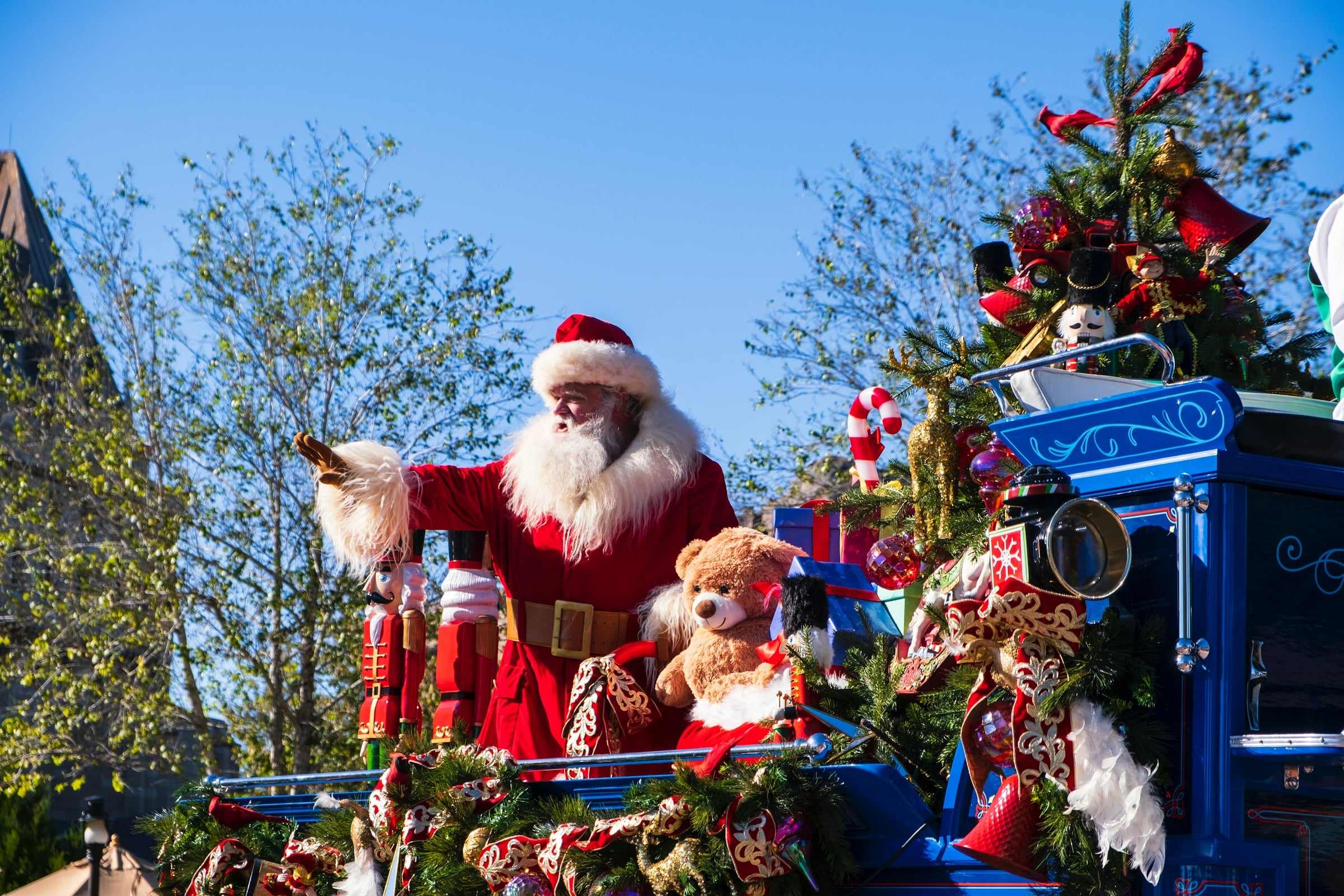 Santa Claus riding a decorated holiday parade float on a sunny street
