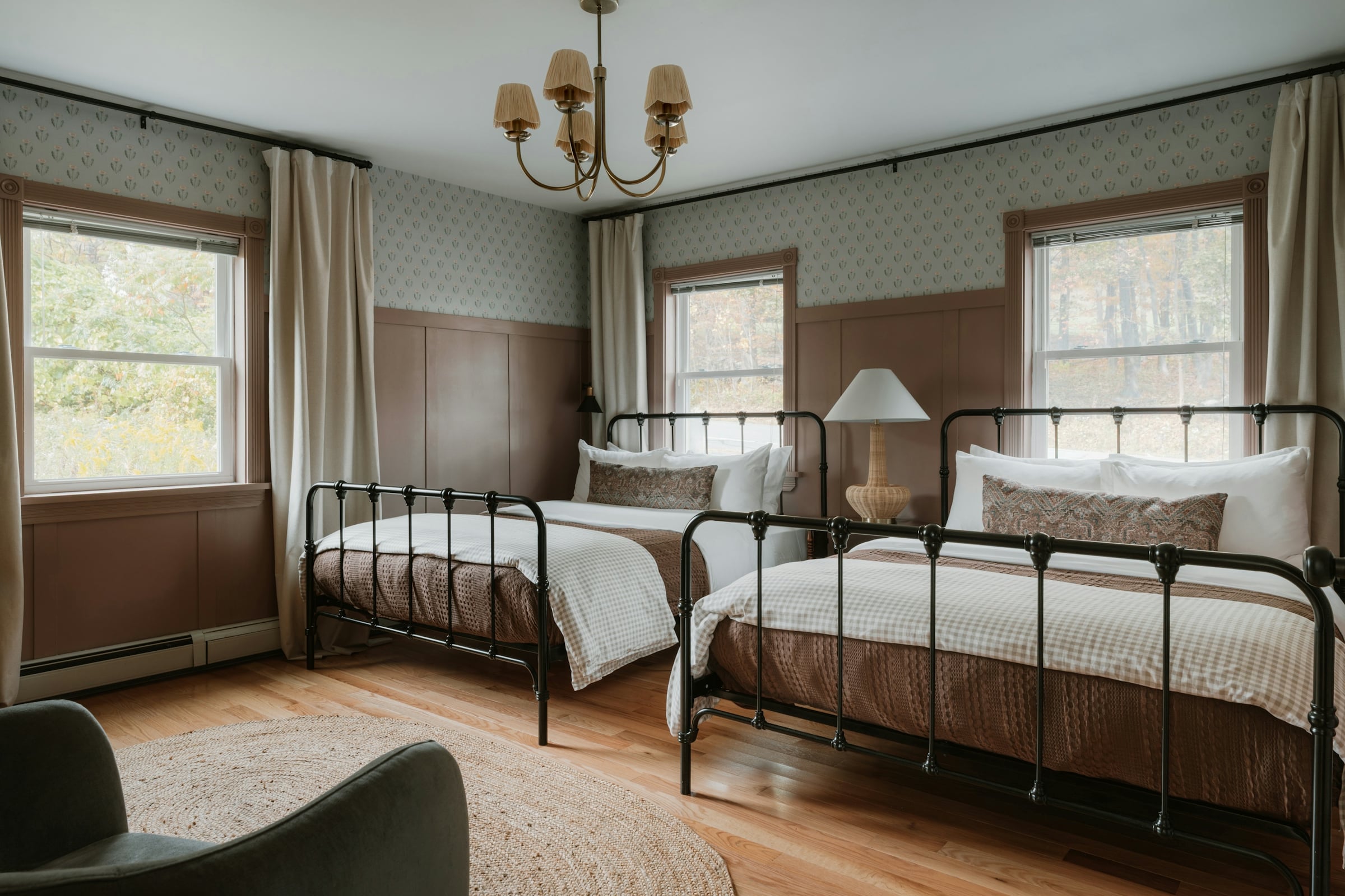 Guest bedroom with two black iron-frame twin beds, a lamp, a chandelier and two windows