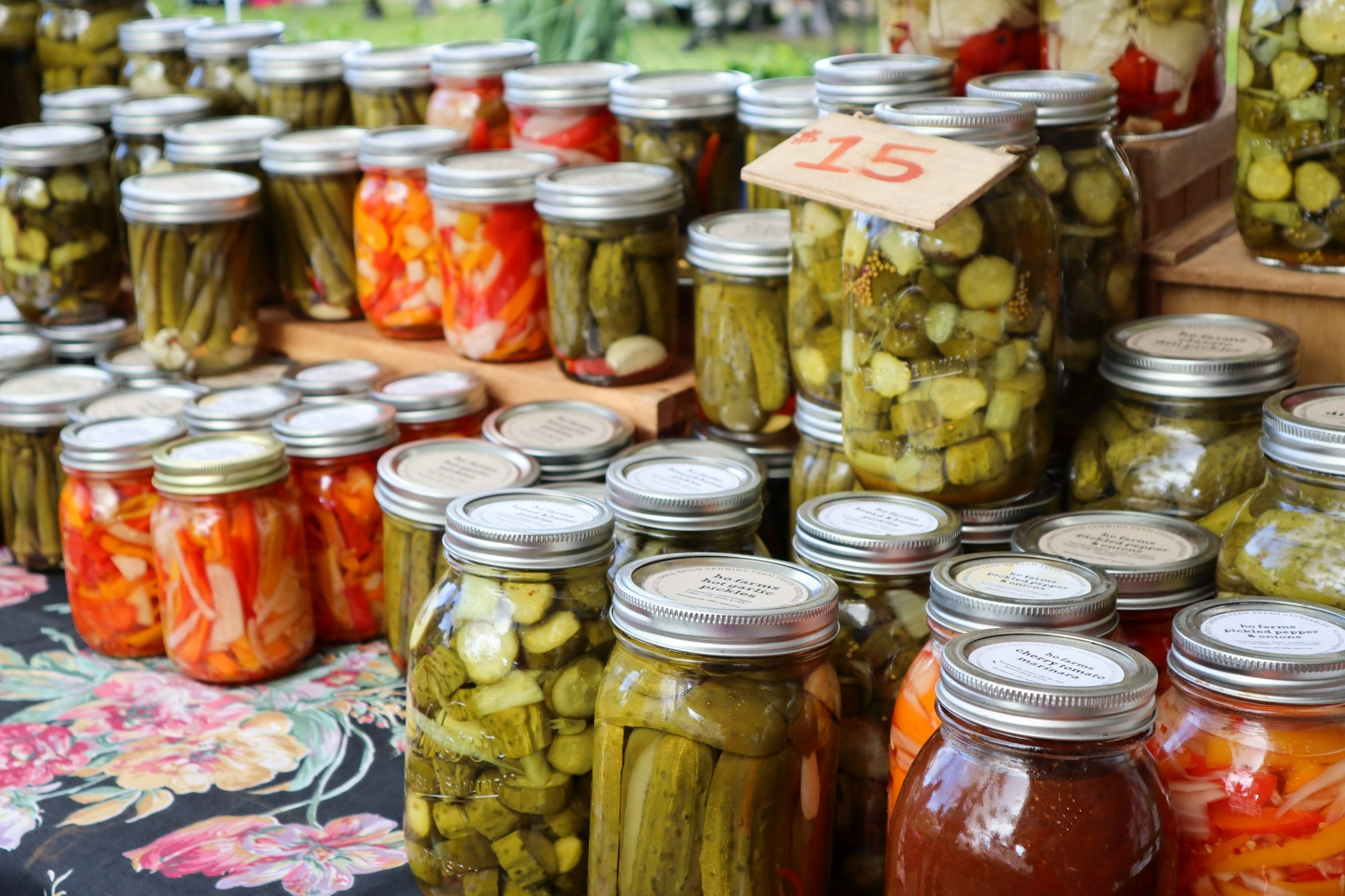 Market table covered with jars of pickled cucumbers and other preserved vegetables