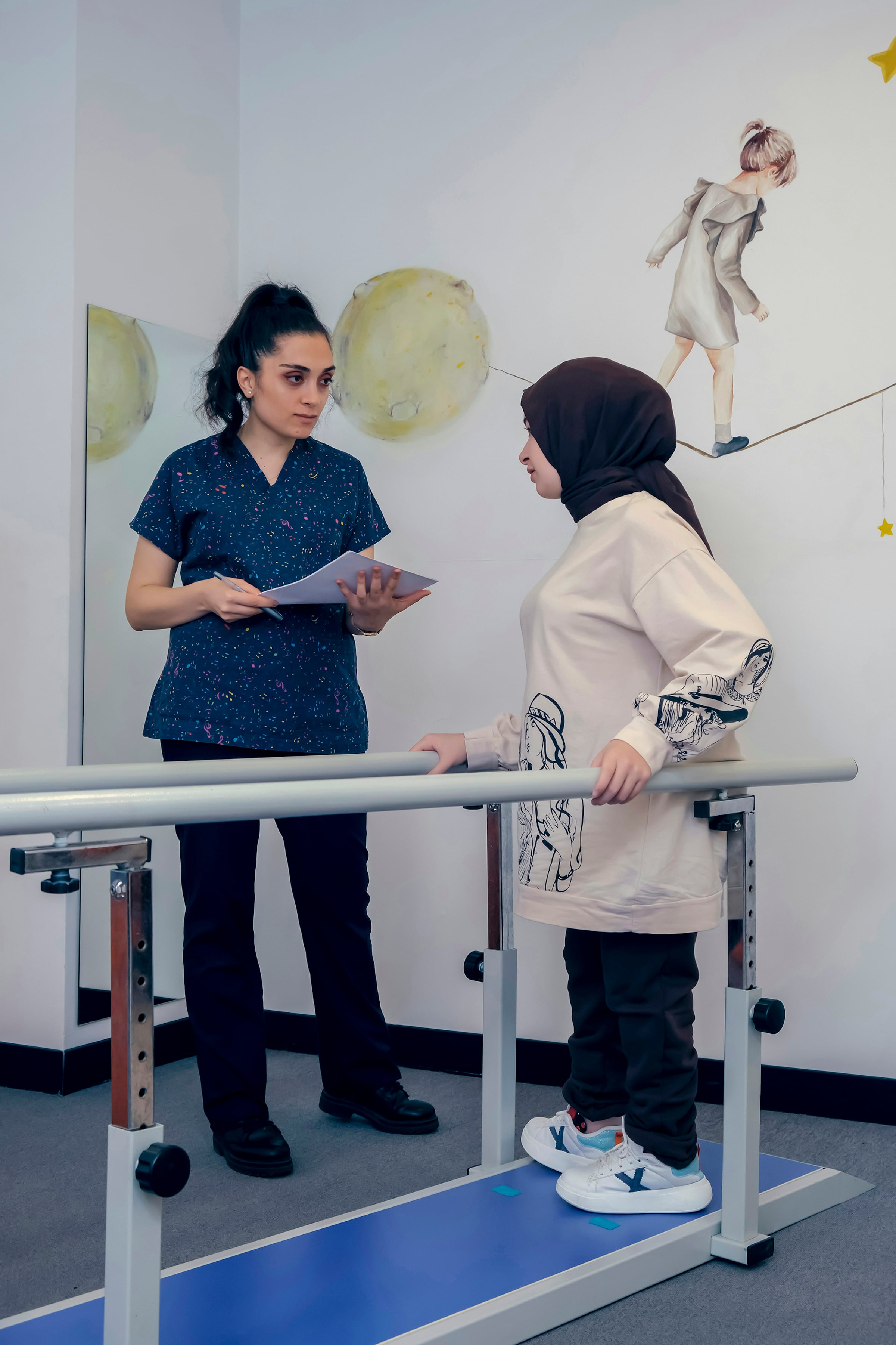 Physical therapist with a patient beside parallel bars in a rehabilitation clinic